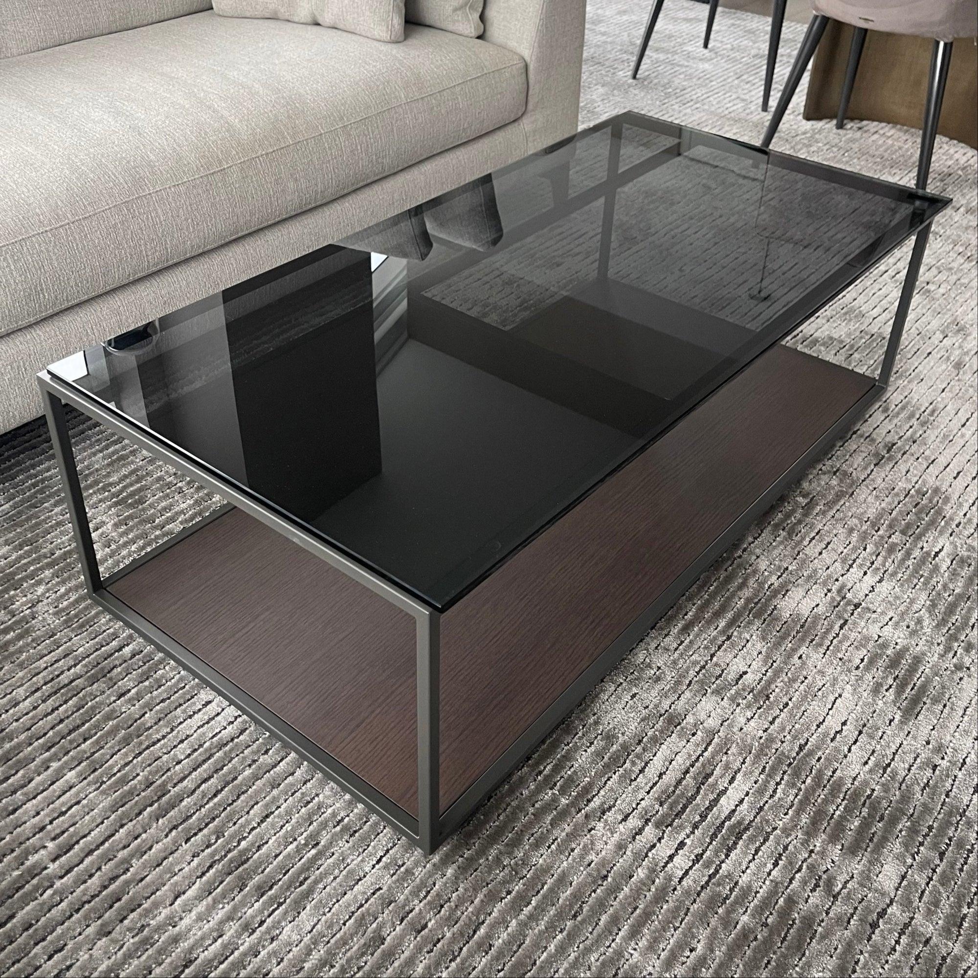 The Rita Lite Coffee Table is a collection of coffee and auxiliary tables featuring a gray smoked glass top and a thermo-lacquered metallic structure, with a sleek black frame perfect for any living space.