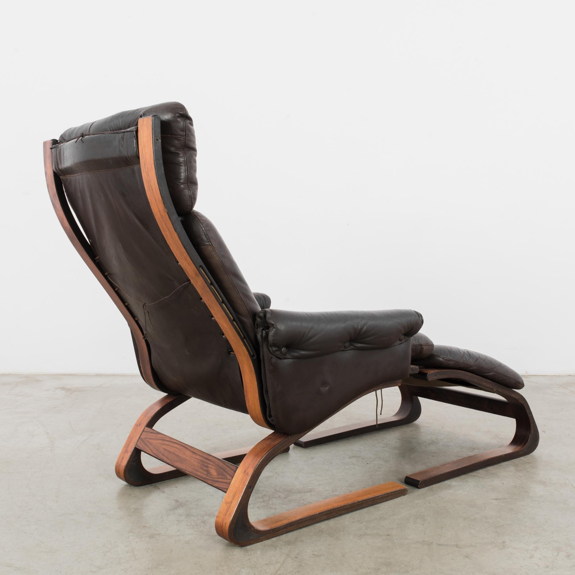 A vintage Kengu lounge chair with ottoman, designed by Elsa & Nordahl Solheim for Rykken and Co., produced circa 1971. Plush, dark brown leather on a frame of laminated bent pine wood makes for chic, modern comfort. Expanding upon Norwegian
