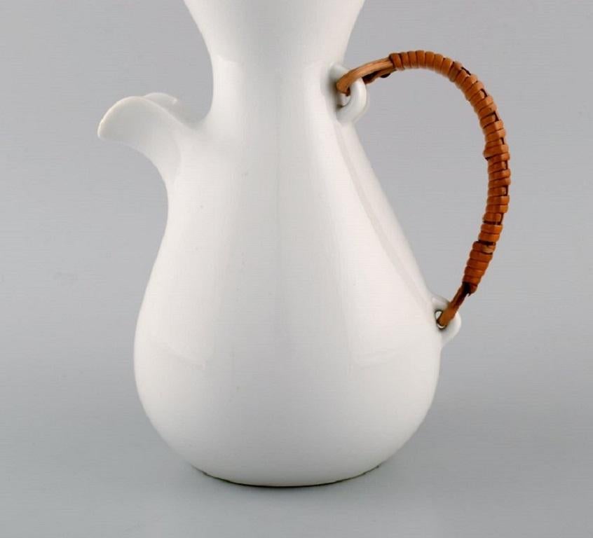 Kenji Fujita for Freeman Lederman. Large modernist jug in white glazed ceramics with a rattan handle. 
Mid-20th century.
Measures: 27 x 17.5 cm.
In excellent condition.
Stamped.
Ceramics manufacturer in California. Founded in 1950 by David W.