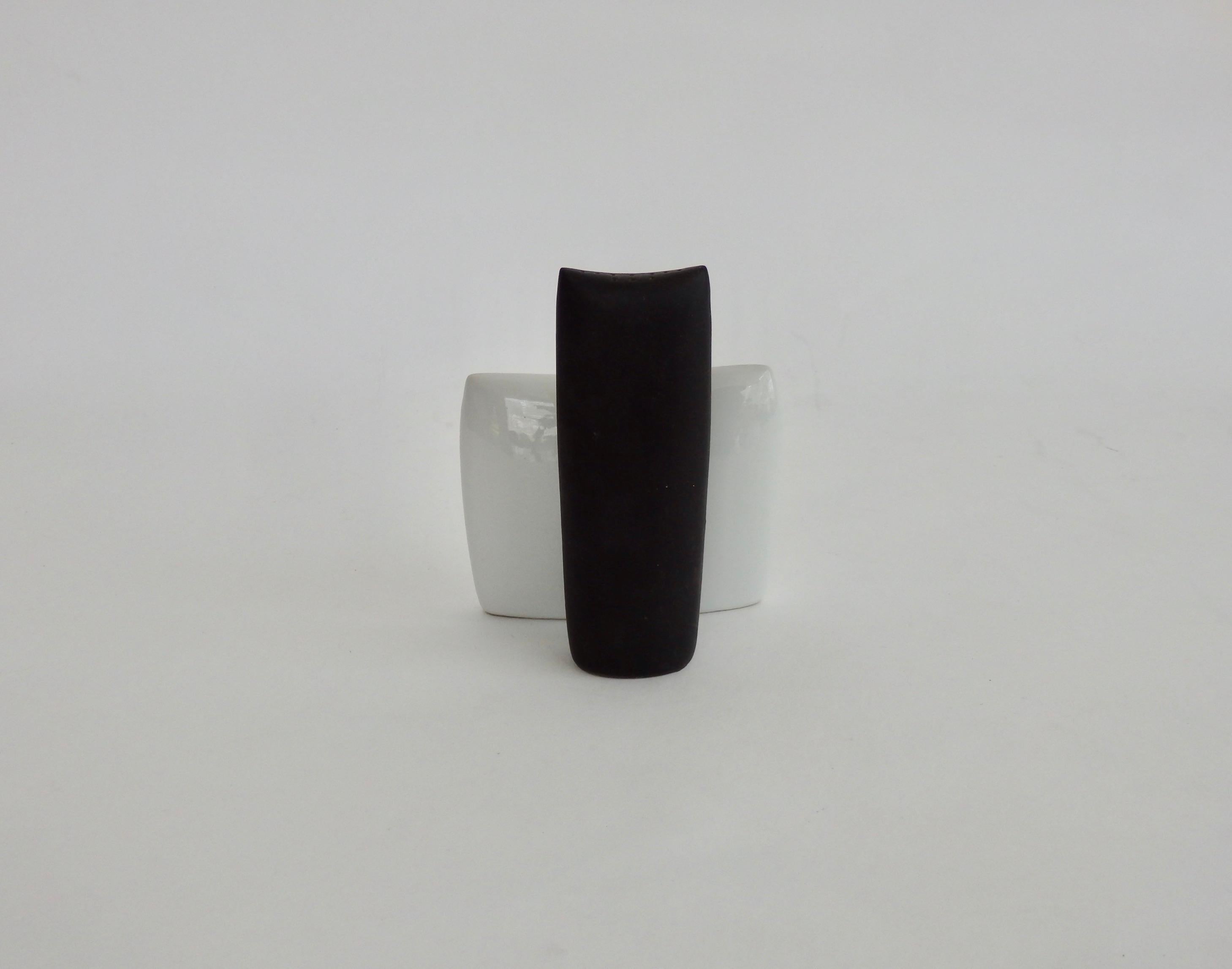 Kenji Fujita design salt and pepper shakers. Pepper in matte black, salt in gloss white glaze. Student of Lagardo Tackett of Architectural Pottery . This set designed for Freeman  Lederman . Tacket.