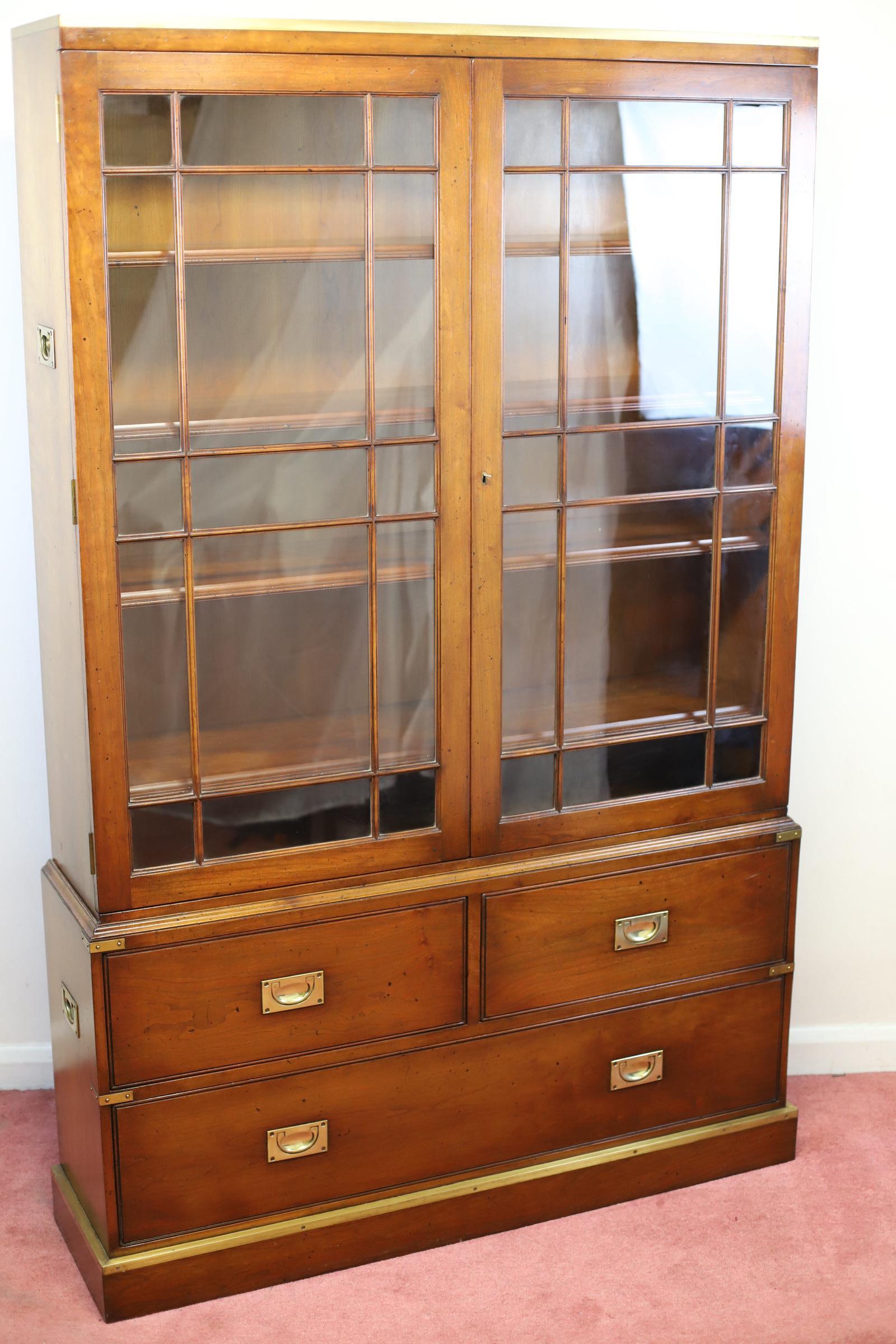 We delight to offer for sale this amazing campaign military style bookcase made by Kennedy of Ipswich and retailed by Harrods in London around 1960 , a beautiful piece of furniture made by walnut and brass , having two tracery glazed doors, four