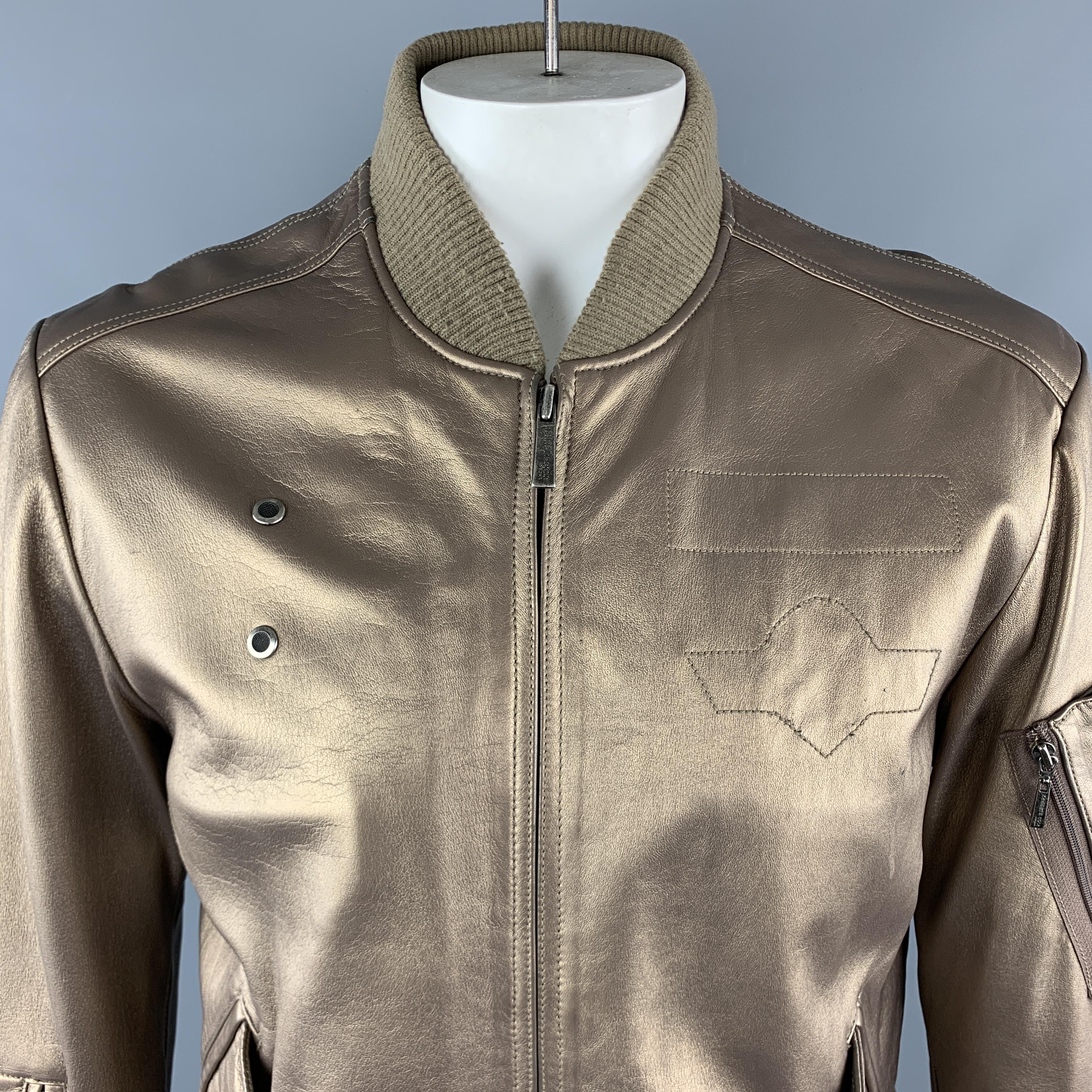 KENNETH COLE VINTAGE Bomber Style Jacket comes in a gold tone in a solid metallic leather material, with a zipped front, single breasted, zip and flap pockets, internal pockets, and ribbed cuffs and hem. Light wear throughout.

Very Good Pre-Owned