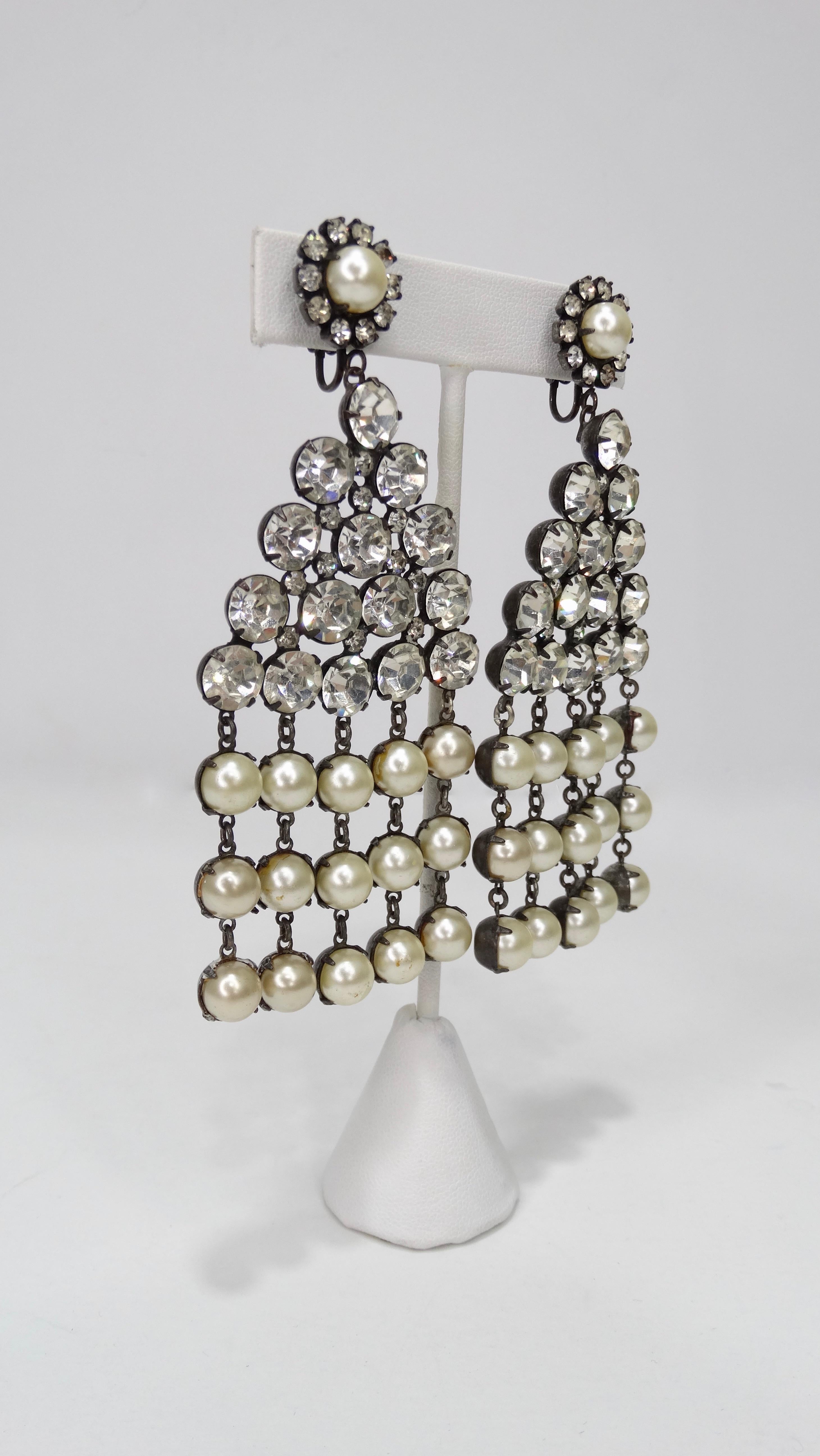 Add some sparkle to your look with these Kenneth Jay Lane earrings! Circa 1960s, these gun metal dangle earrings feature a center rhinestone triangle with free hanging rows of faux pearls. Clip-on back closures stamped KJL. A true pair of vintage