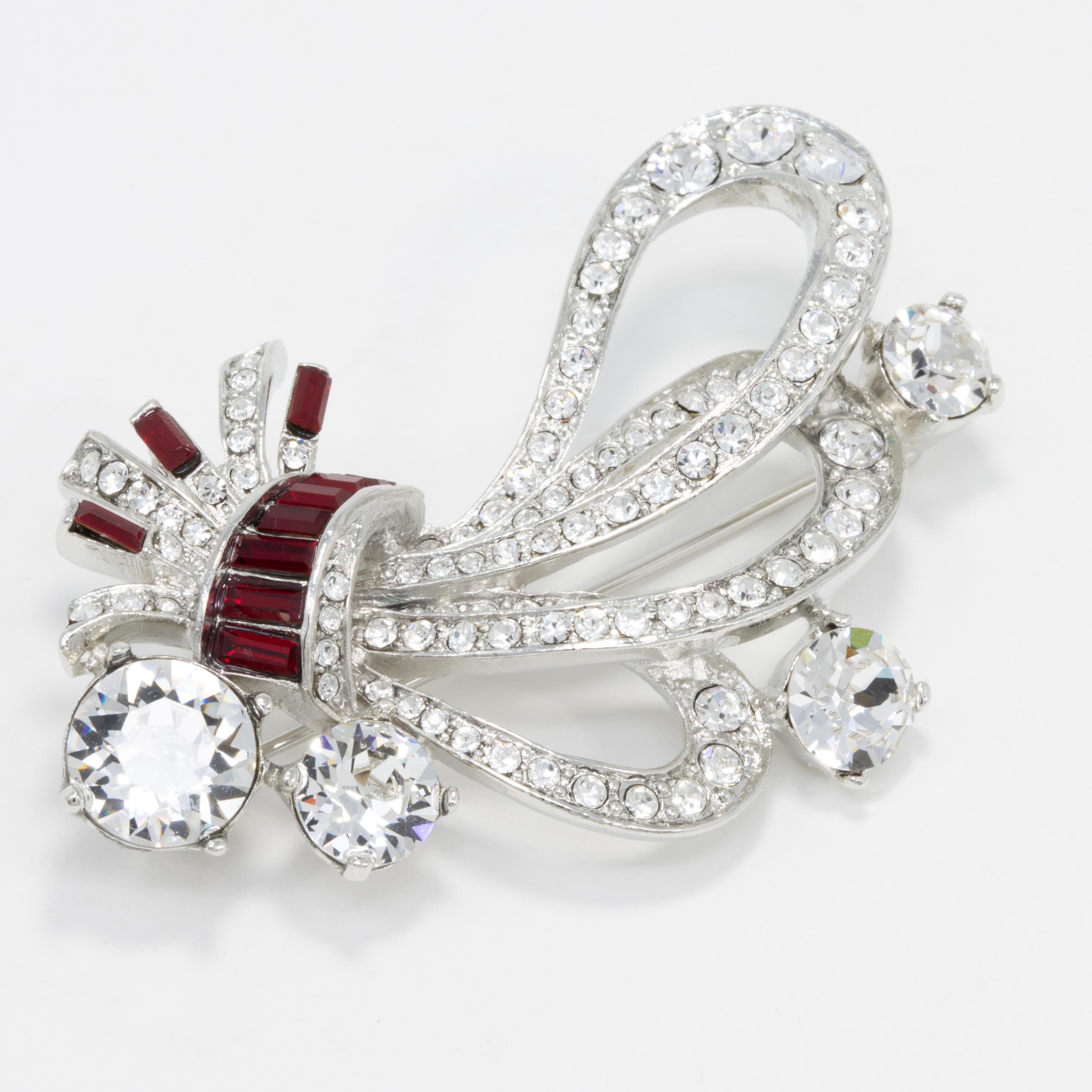 A gorgeous art nouveau-inspired floral pin brooch by Kenneth Jay Lane, featuring dazzling clear and ruby crystals set on a silver-tone bouquet.

Marks / hallmarks / etc: Kenneth Lane, Made in USA