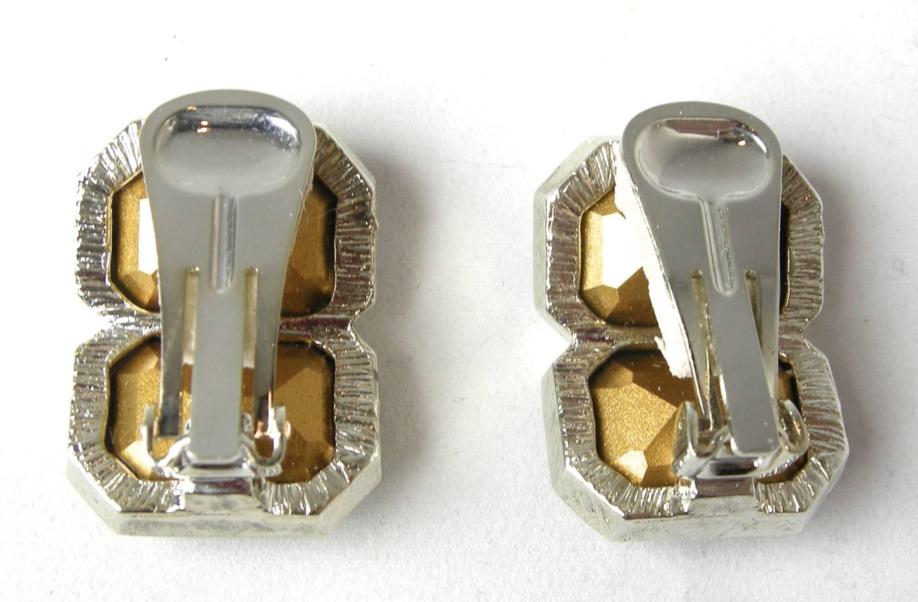The beautiful clip earrings by Kenneth Jay Lane have a two faux sapphire crystals bezel into a curved silver tone metal finish. They measure 1” long x 7/8” wide.  They are signed “Kenneth Lane” and in excellent condition.