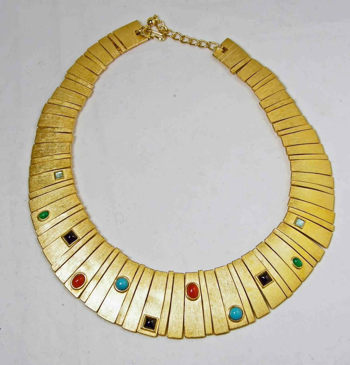 This Kenneth Jay Lane necklace is from his Egyptian revival couture collection.  It is designed in a gold tone setting with the Cleopatra design.  Colorful cabochon stones are bezel set in the front.  The necklace is 16” but can be adjusted to 18”