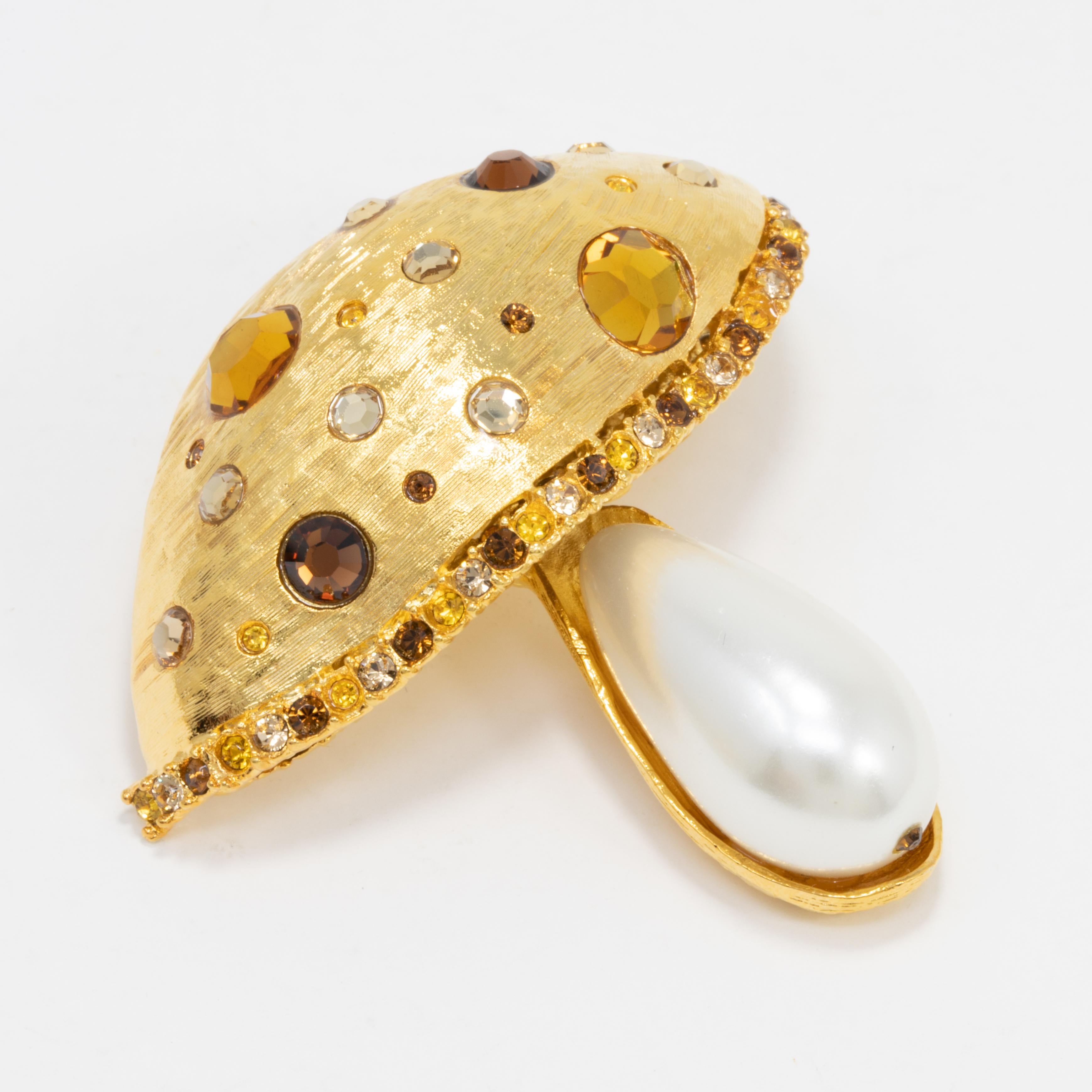 A whimsical golden pin by Kenneth Jay Lane! This glamorous mushroom is decorated with crystals and a single faux pearl.

Marks / hallmarks / etc: Kenneth Lane, Made in USA
