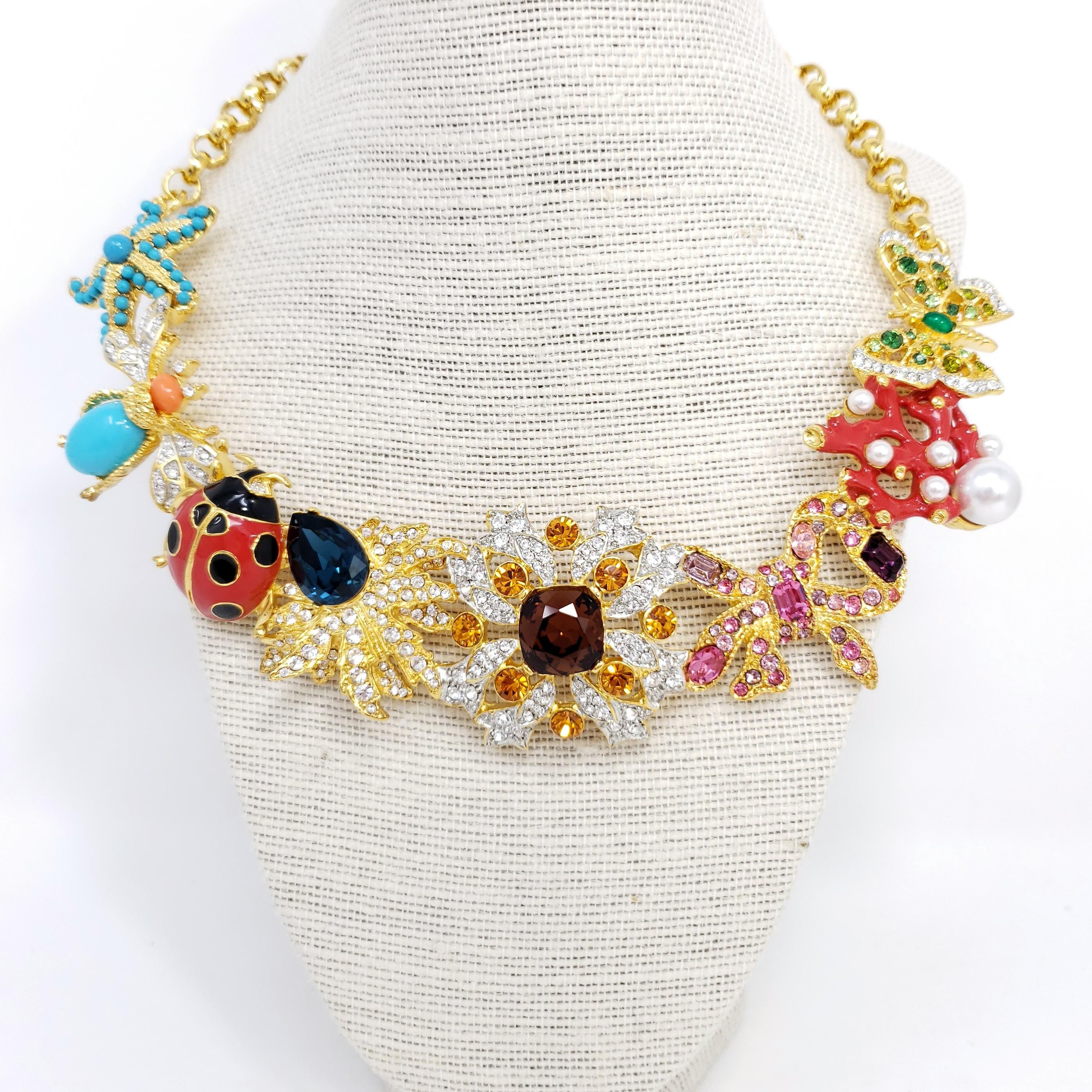 Kaleidoscope necklace by Kenneth Jay Lane. Signature KJL designs linked together to form a dazzling statement necklace! Colorful starfish, fly, ladybug, butterfly, coral, flower, and leaf motifs.

Features faux pearls, painted enamel, cabochons and