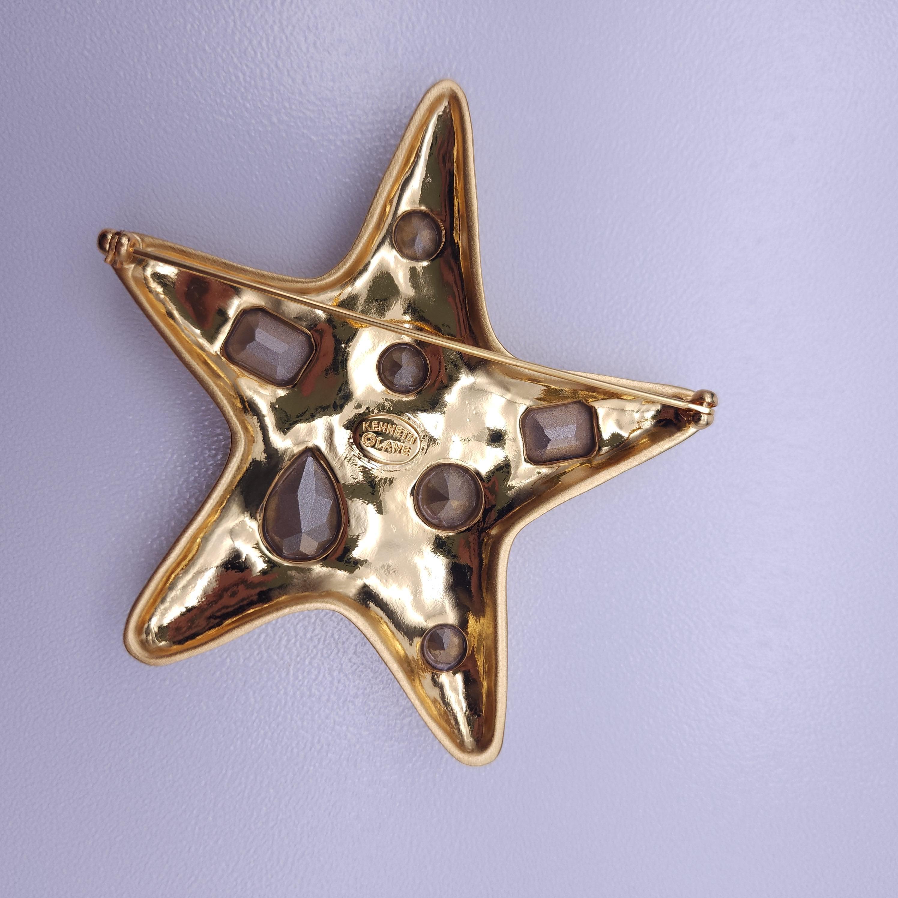 Add a touch of ocean-inspired elegance to your collection with this stunning Kenneth Jay Lane Starfish Brooch. Crafted with a luxurious gold-tone finish, this brooch showcases a whimsical starfish design, adorned with sparkling crystal accents. The