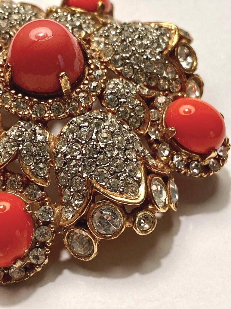A stunning 1960s Kenneth Jay Lane domed medallion brooch in rich gold plate with faux coral cabochons and rhinestones. The brooch is large and measures 2.63 inches wide and high.. Including the pin backing, it is 1.25 inches deep. The cabochons are