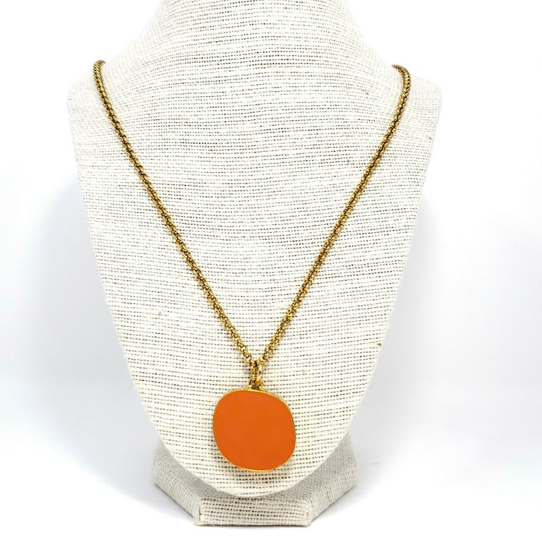 A Stylish faux coral gold bezel pendant necklace by Kenneth Jay Lane. The chic pendant hangs on a 60 cm /23.5 in gold-plated link chain.

Hallmarks: Kenneth Lane