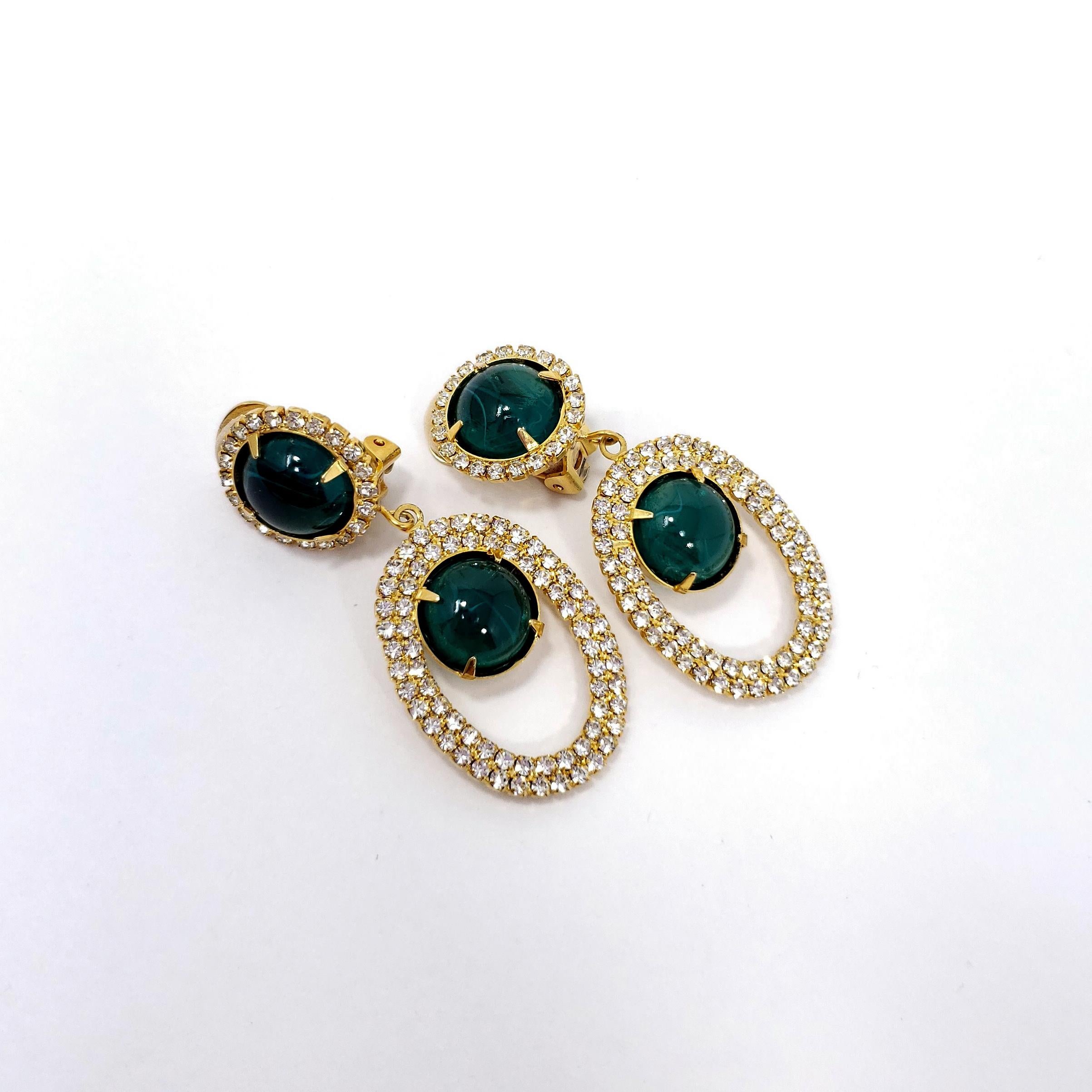 Stylish dangling clip on earrings by Kenneth Jay Lane. Each earring features opaque green cabochons accented with clear crystals. All set in gold-plated metal.

Hallmarks: Kenneth Lane