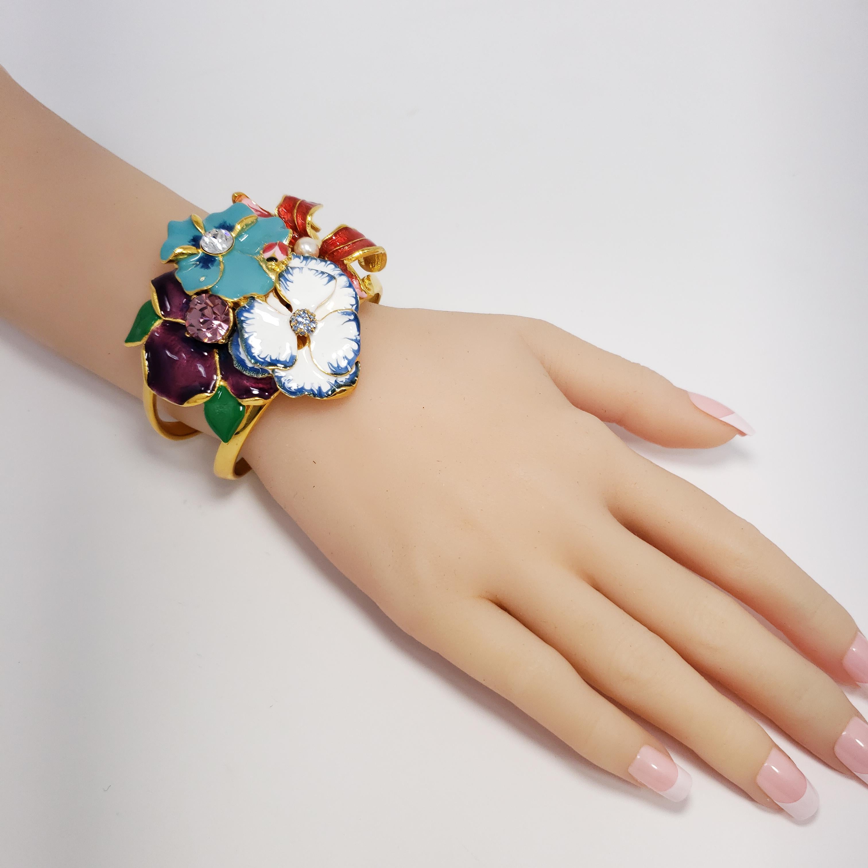 A bracelet by Kenneth Jay Lane featuring an assortment of painted enamel flowers accented with crystals in gold. 

Diameter at widest part: 6.0 cm/ 2.4 in
Inner circumference: 16.5 cm / 6.5 in 

Hallmarks: Kenneth Lane