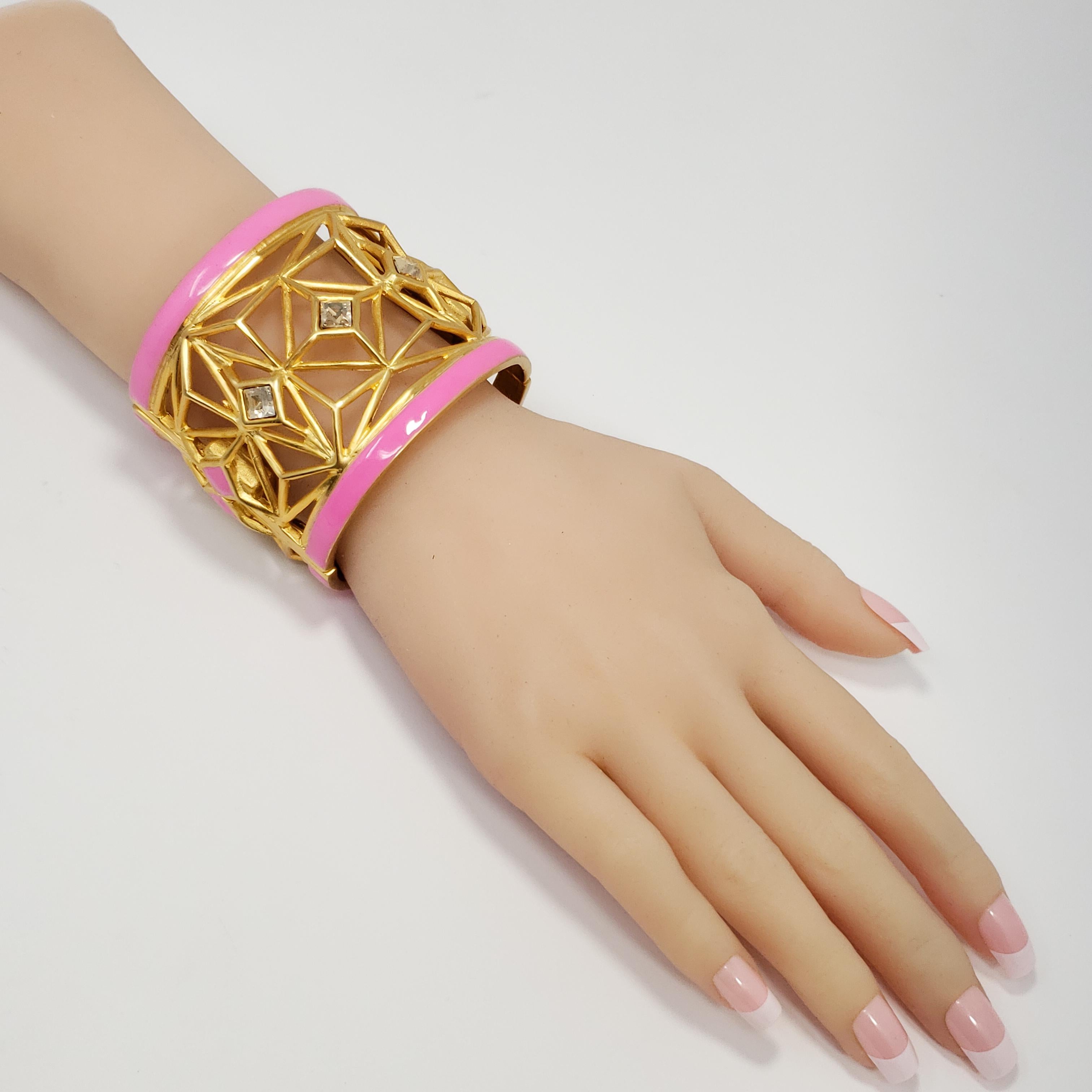 Ein Armband von Kenneth Jay Lane mit eleganten geometrischen Mustern in Gold, die mit rosafarbenen Harzakzenten und rauchigen Topaskristallen verziert sind.

Höhe: 5,9 cm / 2,3 in
Durchmesser an der breitesten Stelle: 5.9 cm/ 2.3 in
Innerer Umfang: