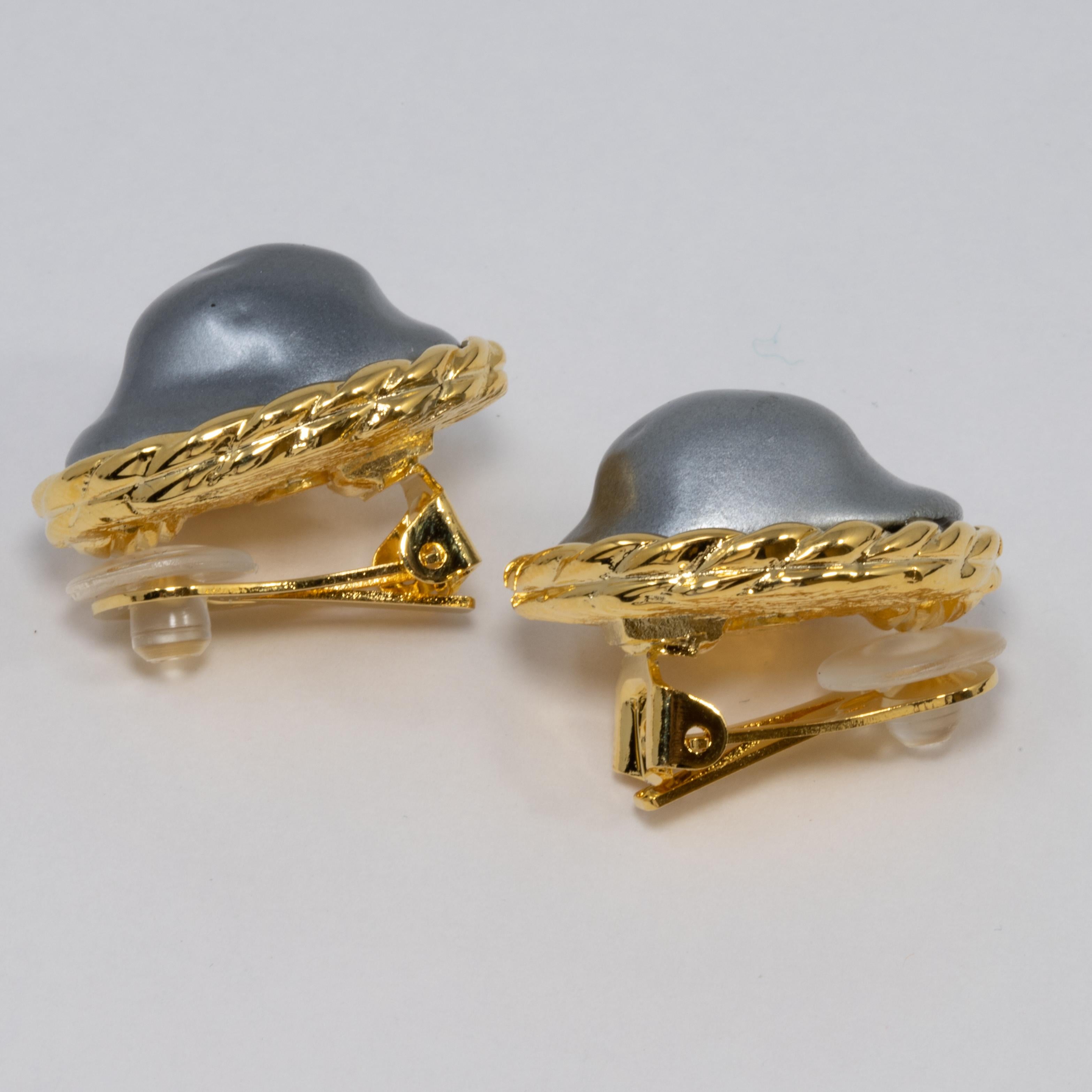 Earrings by Kenneth Jay Lane. Grey resin mother of pearl centers set in decorative gold-plated bezel. Clip ons.

Hallmarks: Kenneth Lane, Made in USA