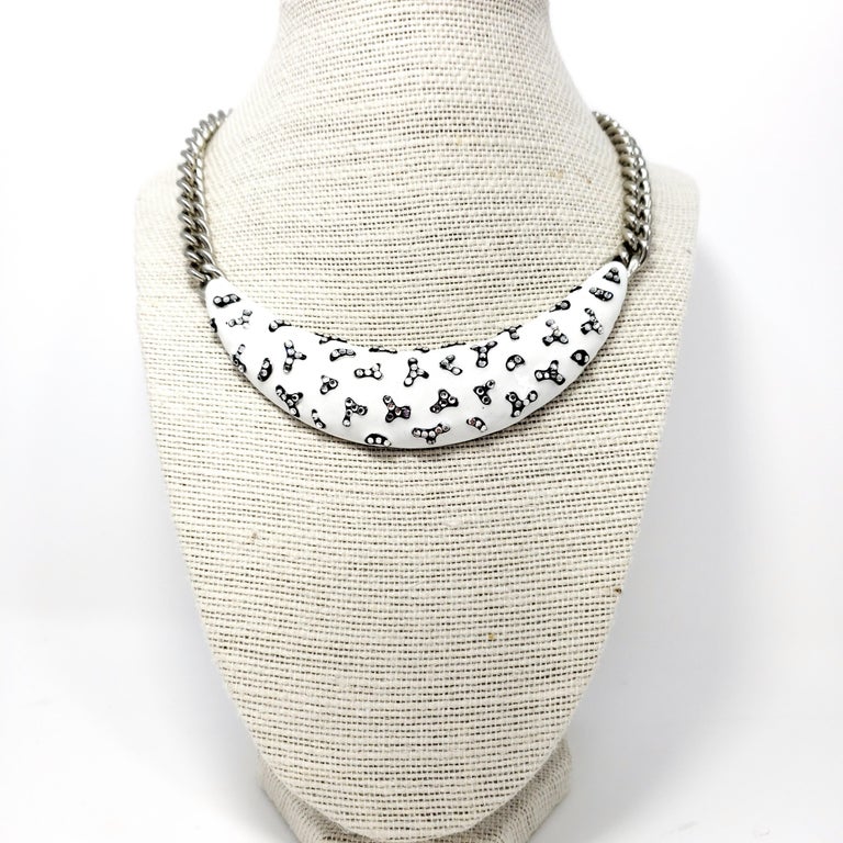 Embellished collar necklace, featuring a white and black enamel centerpiece accented with clear crystals. Silver-tone chain. From Kenneth Jay Lane.

Length: 42 cm + 9.5 cm extension

Hallmarks: Kenneth Lane