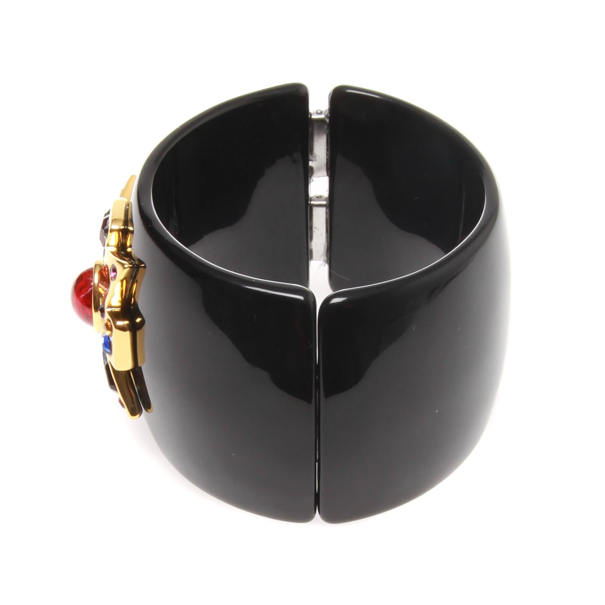 An immaculate black Swarovski embellished cuff bracelet by KENNETH JAY LANE.
Intricately crafted with large gold-plated Maltese cross with multi coloured crystal embellishments, and features a magnetic clasp closure.