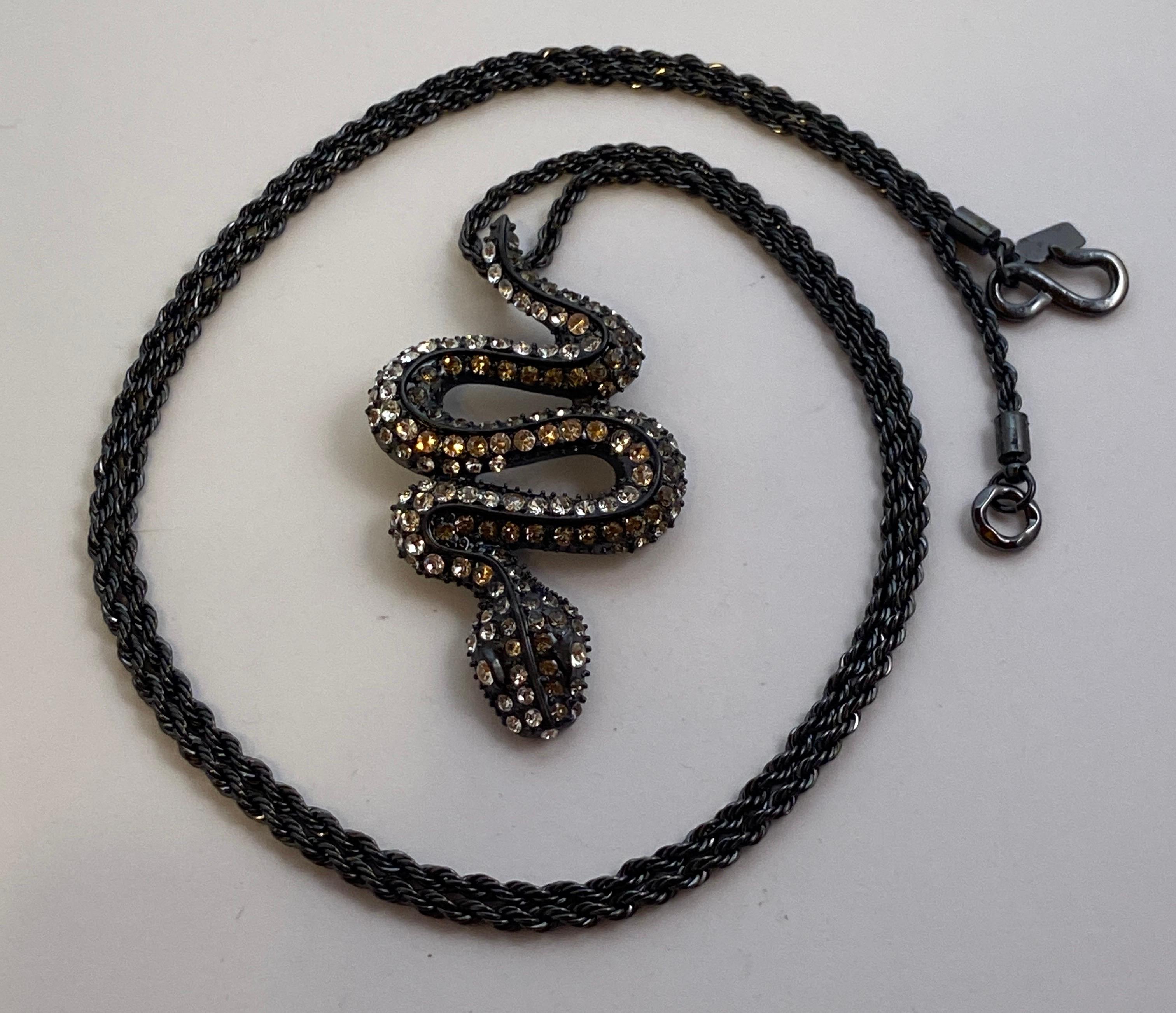    Kenneth Jay Lane's medium-size black 'snake' encrusted with rhinestones pendant hangs whimsically on a black rope hardware necklace. The necklace measures 34 inches in total length. The pendant measures 2 5/8 inches in length, width measures 1 