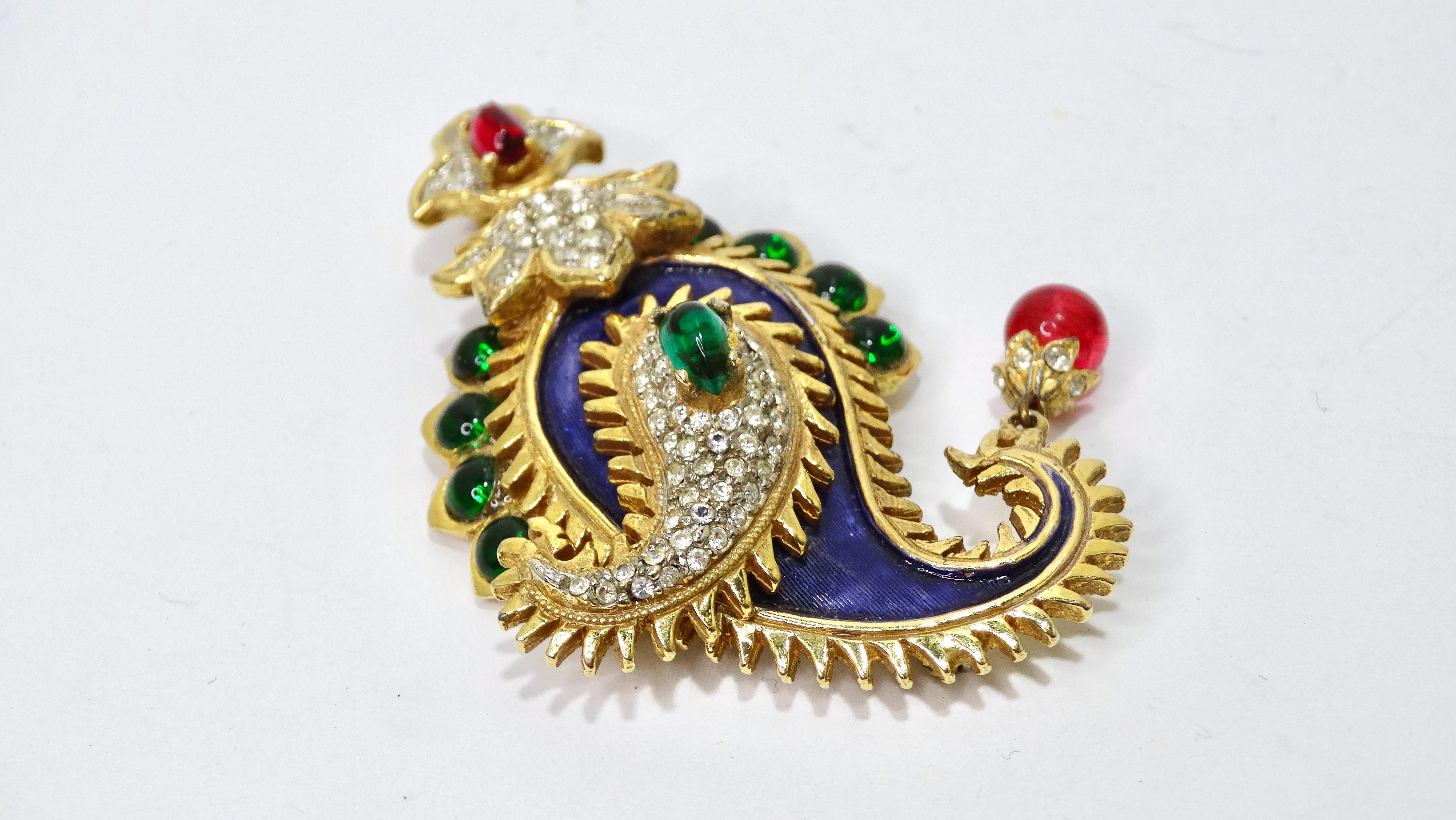 This is a spectacular find from none other than Kenneth Jay Lane! This paisley Maharani Kenneth Jay lane brooch features, and green ruby glass beads, pave rhinestones and purple enamel embellishing. Attached to it is a red bead shaped dangling