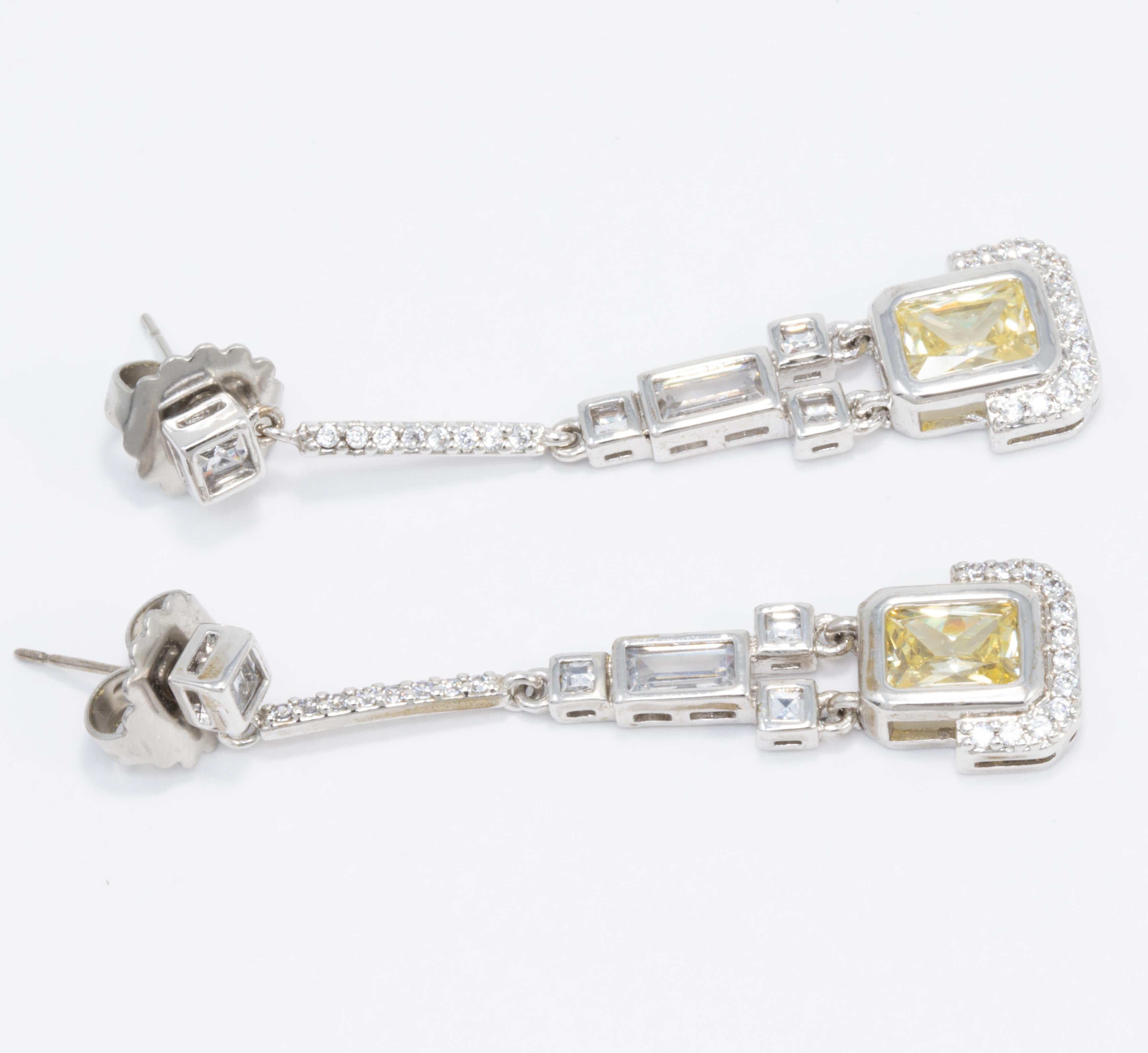 Add some sparkle to your outfit with these Art-Deco style silver tone drop earrings by Kenneth Jay Lane.

Clear and jonquil cubic zirconia crystals. Post backs.

Marks/Hallmarks: KJL

CZ by Kenneth Jay Lane line. Designed in New York. Made in China.