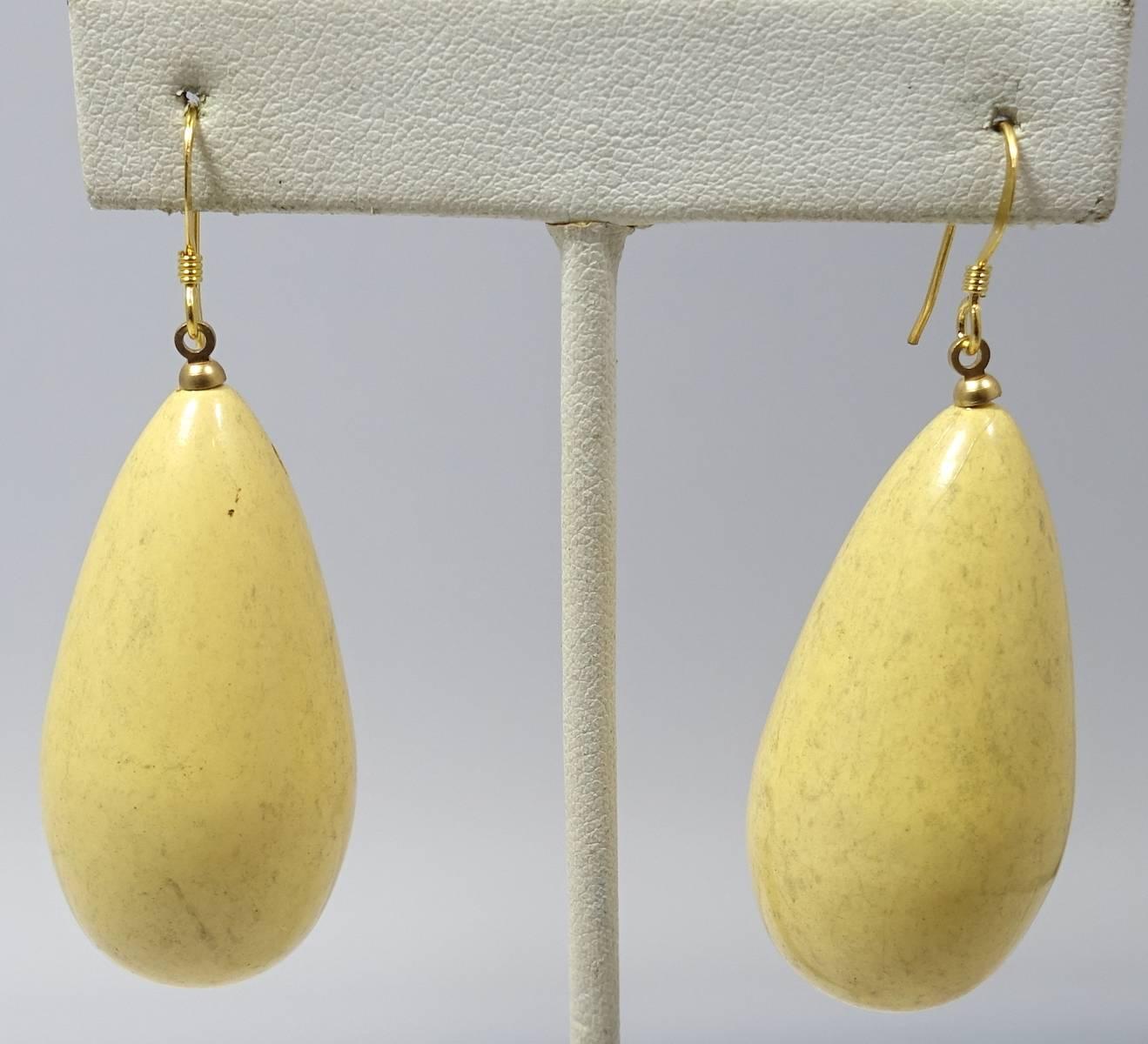 These Kenneth Jay Lane pierced earrings feature a teardrop design in a yellow marbleized natural wood and gold tone setting.  These earrings measure 2” x 1” and are in excellent condition.
