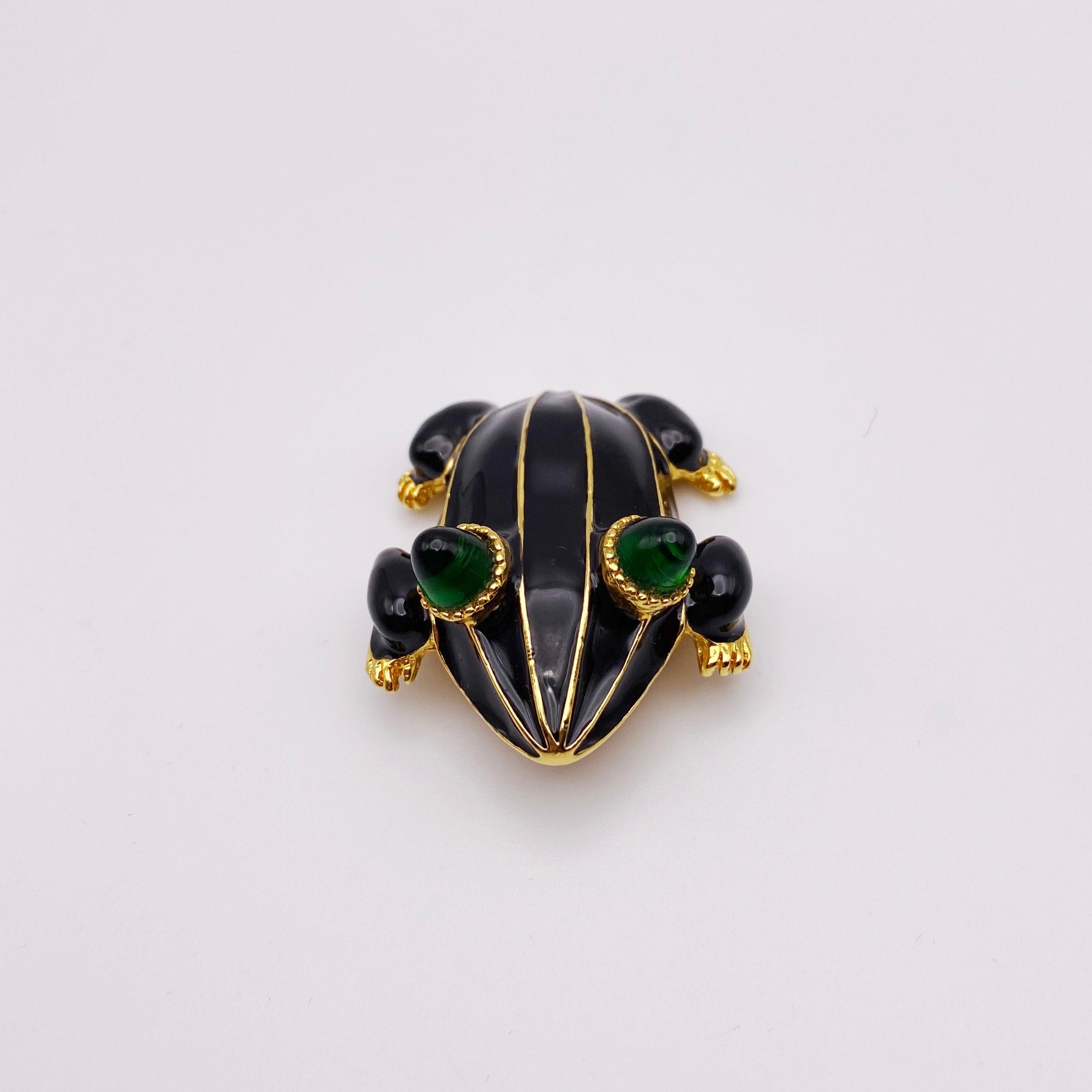 Circa 1990s. A striking black enamel and emerald glass eye frog brooch by legendary designer, Kenneth Lane. Gold plated. Excellent condition. A beautiful gift or treat for yourself! 