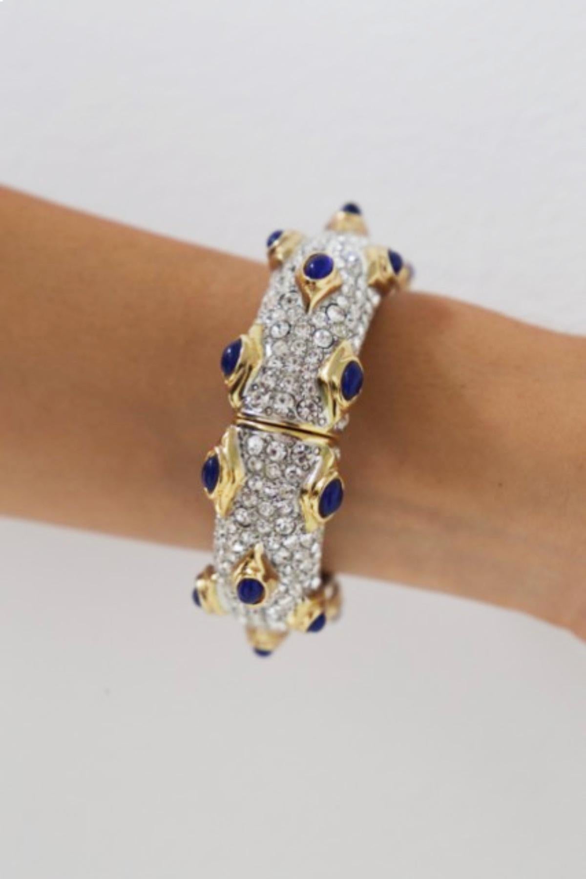 Royal bracelet designed by Kenneth Lane in the 1990s, ORIGINAL BRAND.
The bracelet has a round shape and opens and closes by a magnetic mechanism.
The jewelry is studded with small white cubic zirconia, with ocean blue stones set in the metallic