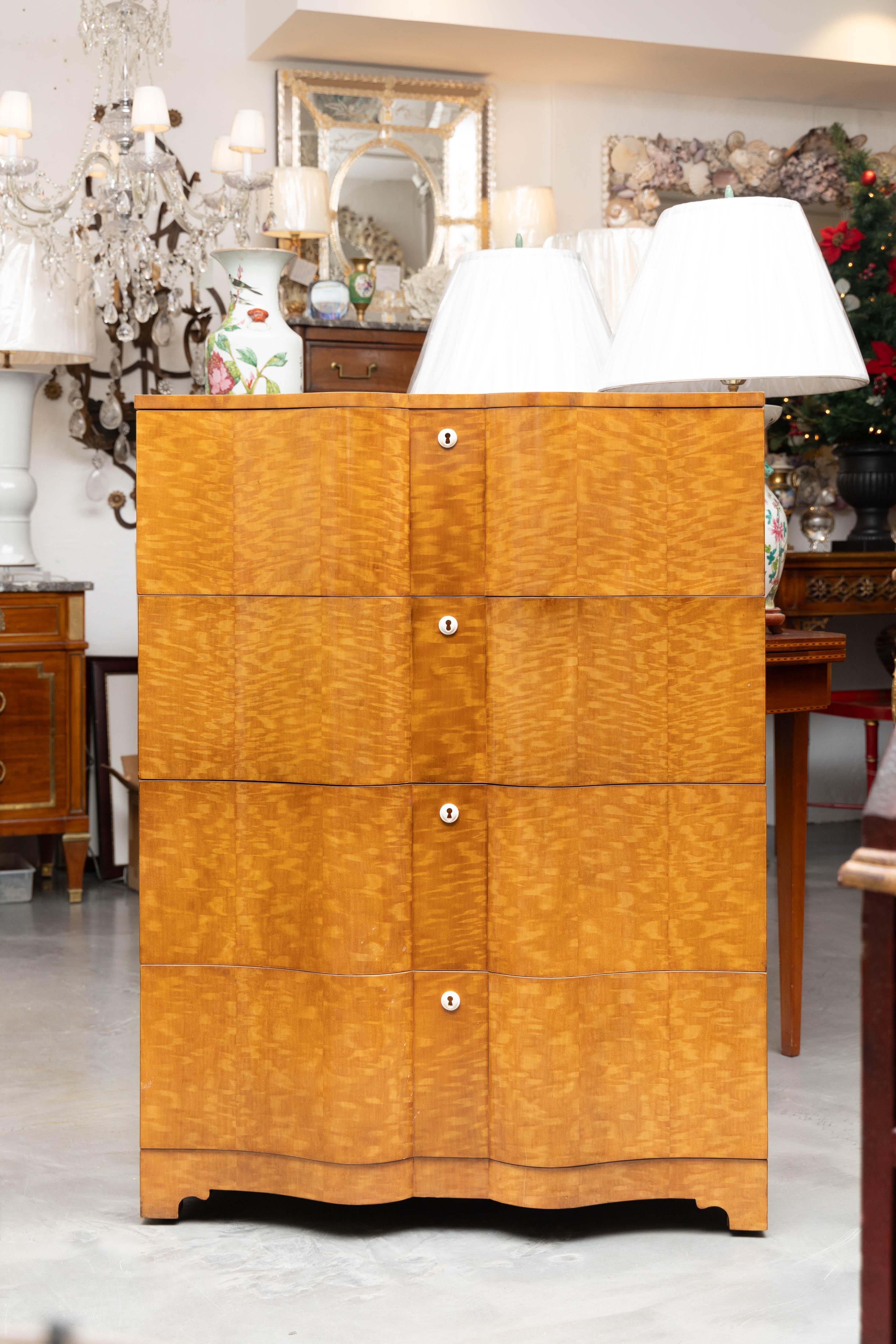 A contemporary chest of drawers dresser commode produced in the Art Deco style designed for the Keno Brothers Collection. A classic serpentine front maple veneer chest featuring four vertical drawers with spacious interiors, with decorative lock