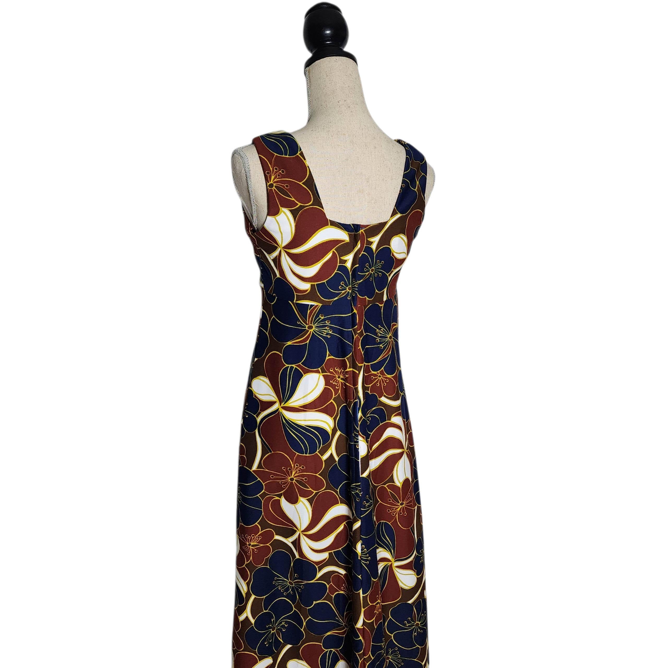 Cette robe longue Kenolo Fashions des années 1970, fabriquée et stylisée à Hawaï, capture l'essence du glamour tropical vintage. La robe présente un imprimé floral audacieux et ludique dans des tons riches de bleu marine, de bordeaux, de jaune