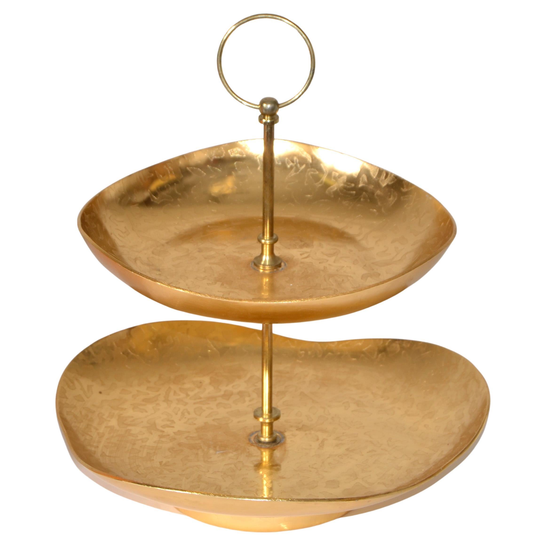 Charming Gold Plate 2 tier Center Handled snack, pastry, cake treats stand or serving tray designed by Lurelle Guild. 
The textured free-form biomorphic relief design looks very Mid-Century Modern and was made from 1934 to 1965.
Beautifully coupe