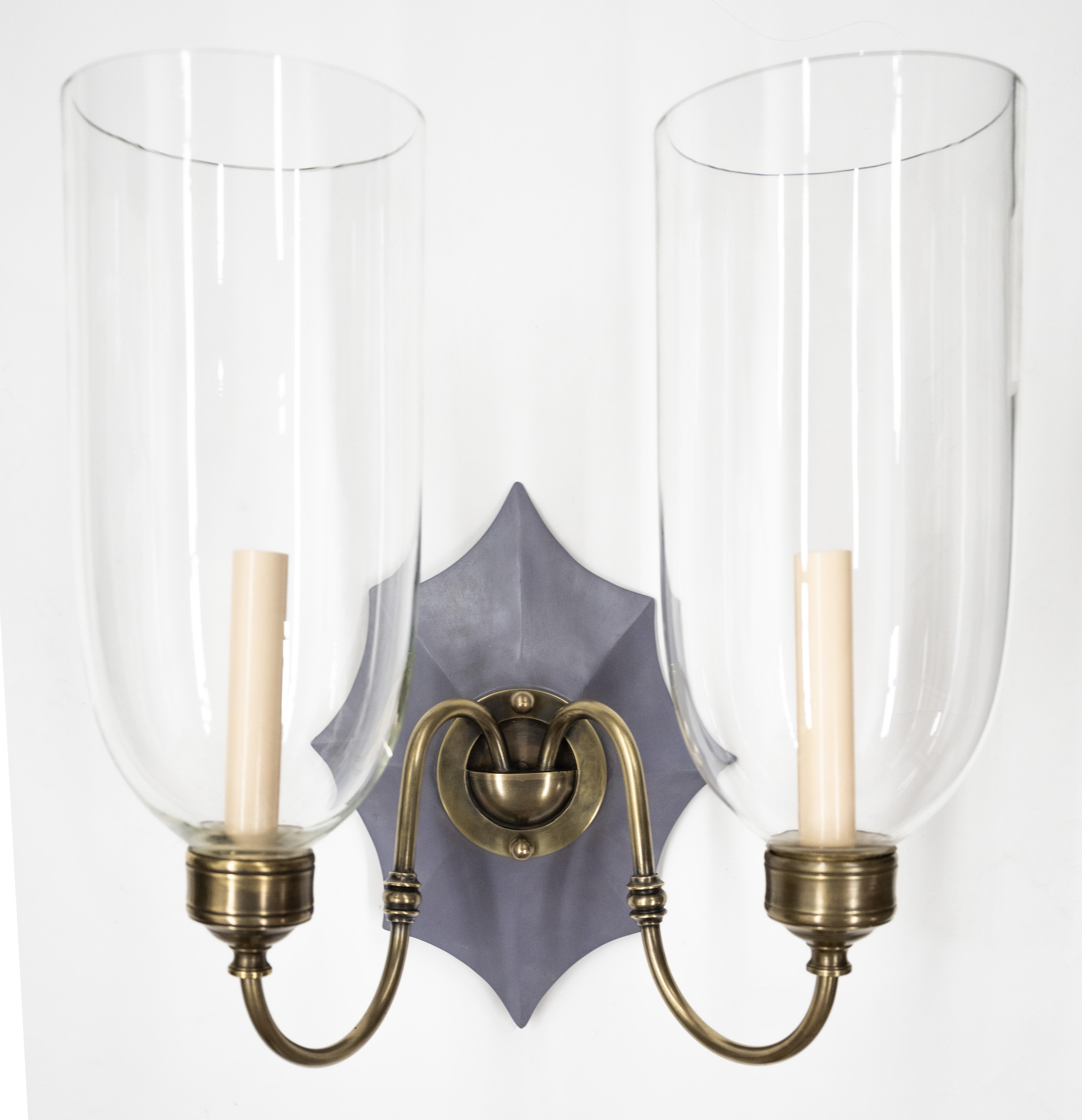 A pair of hand-carved Boissy sconces from mahogany Georgian-style backplates with a painted finish, patinated brass sconce fittings, and hand-blown shades. Electrified with two candelabra-based socket per sconce. Our custom hurricane sconces are