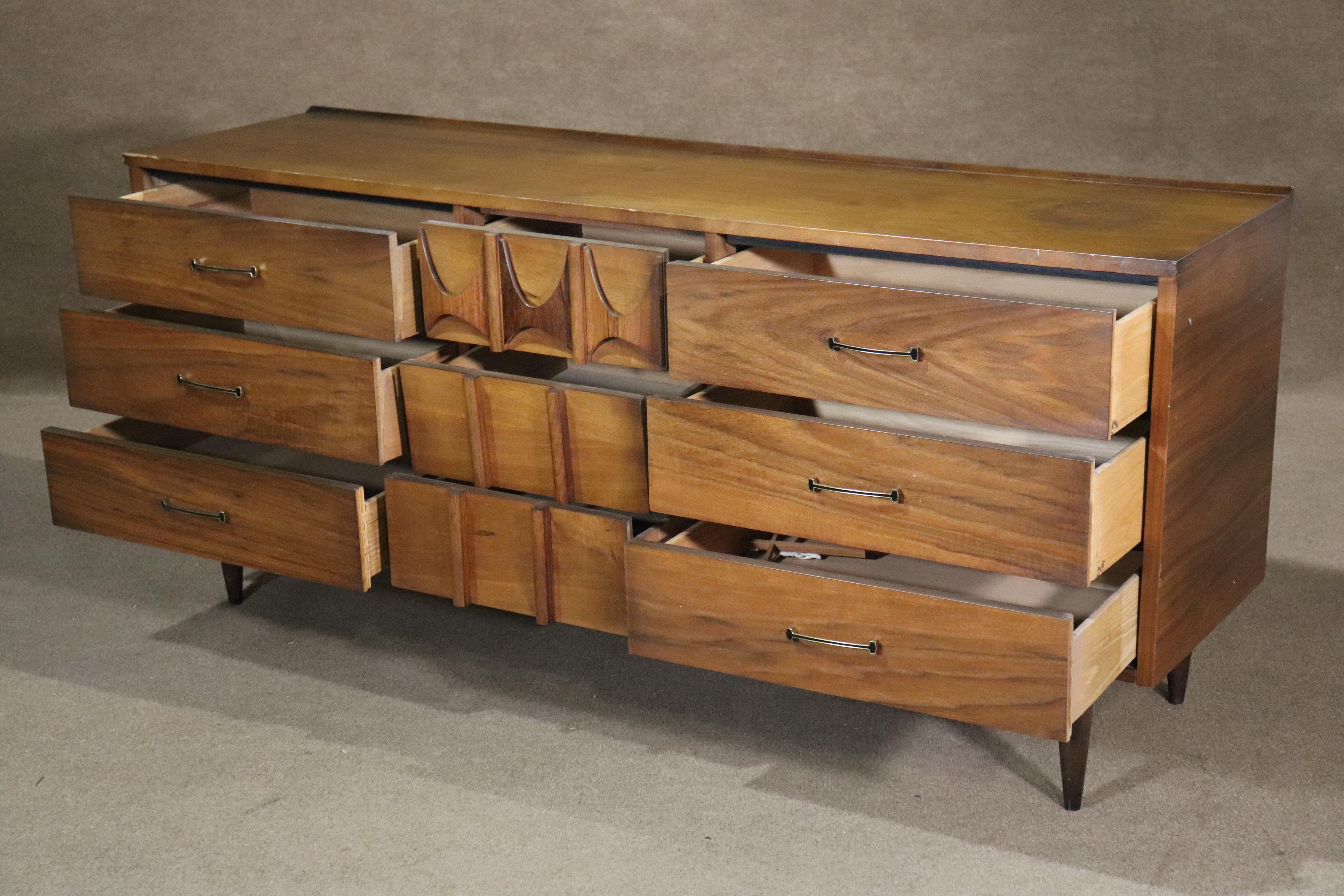Commode longue à neuf tiroirs, de style moderne du milieu du siècle, conçue par Kent Coffey pour sa ligne 'Brasilia'. Cette commode présente les accents de bois courbé typiques de Brasilia, ainsi que des ferrures en métal et des pieds