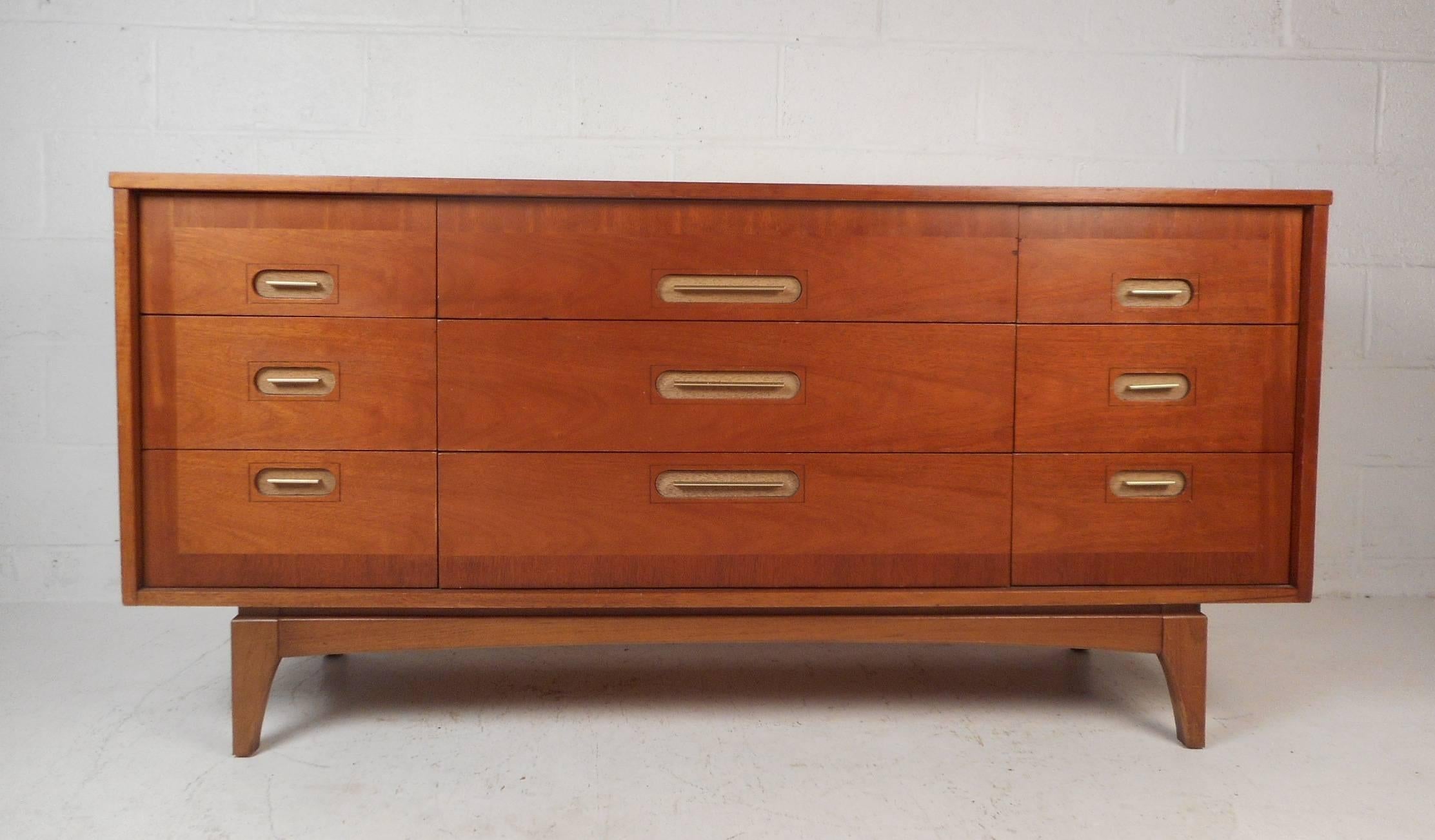 This beautiful Mid-Century Modern dresser features unique oval recessed pulls on each of its nine drawers. The drawer fronts have wood grain running in a different direction around the perimeter adding a unique quality to this piece. Quality