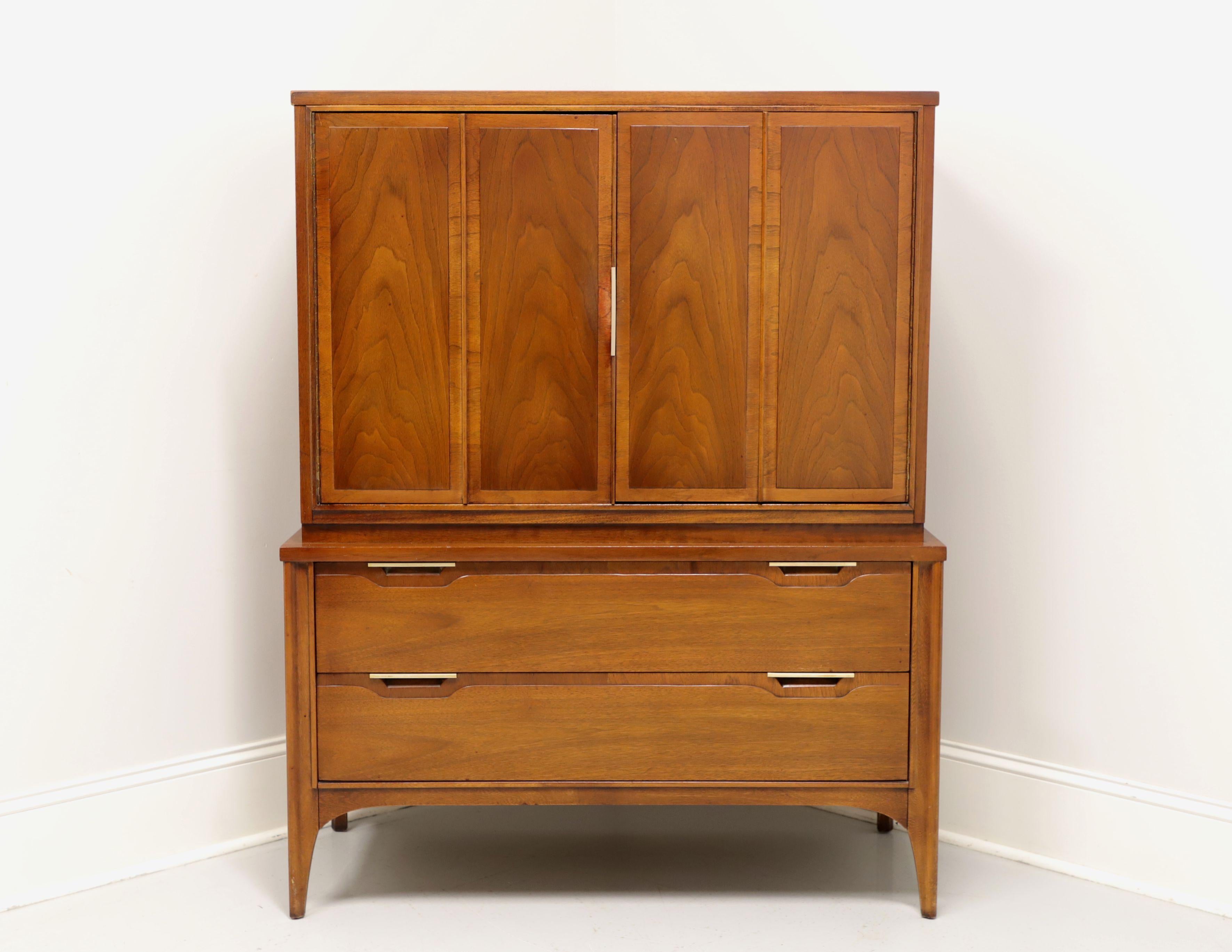 A Mid Century Modern gentleman's chest by Kent Coffey, of Lenoir, North Carolina, USA, from their Impact line. Walnut, elm and brass hardware with banded door fronts. Features upper section with dual doors revealing three fixed cubbies and two