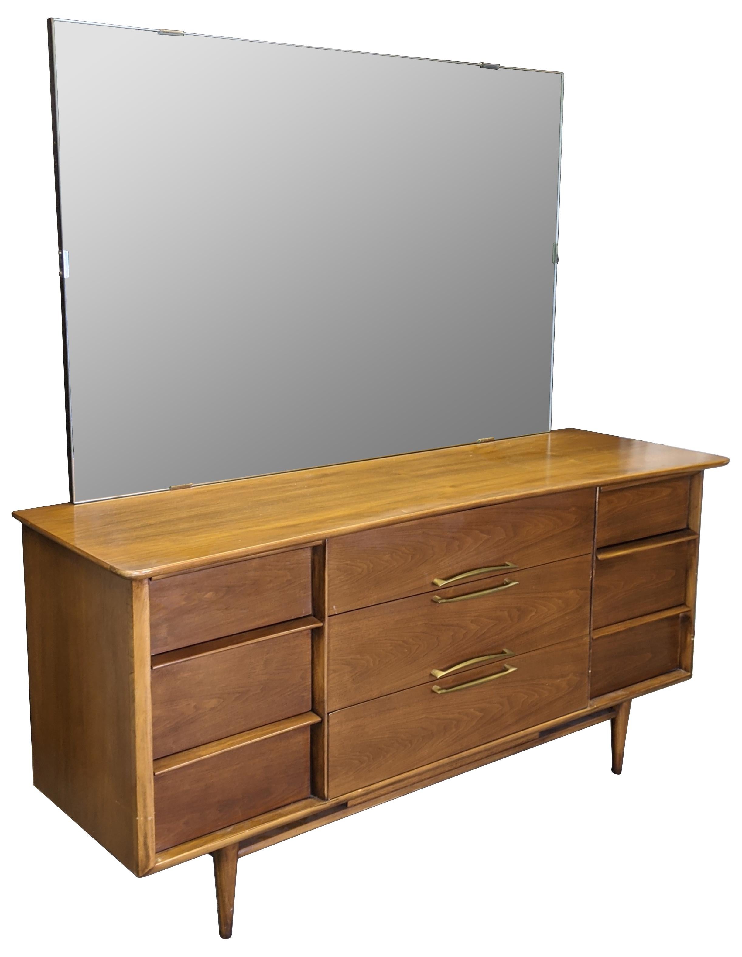 Vintage sculptural shaped mirrored vanity, dresser or buffet by Kent Coffee. Made from continental walnut with dovetailed drawers, tapered legs and large mirrored back, circa 1960s. #6902.

Measures: Mirror 54