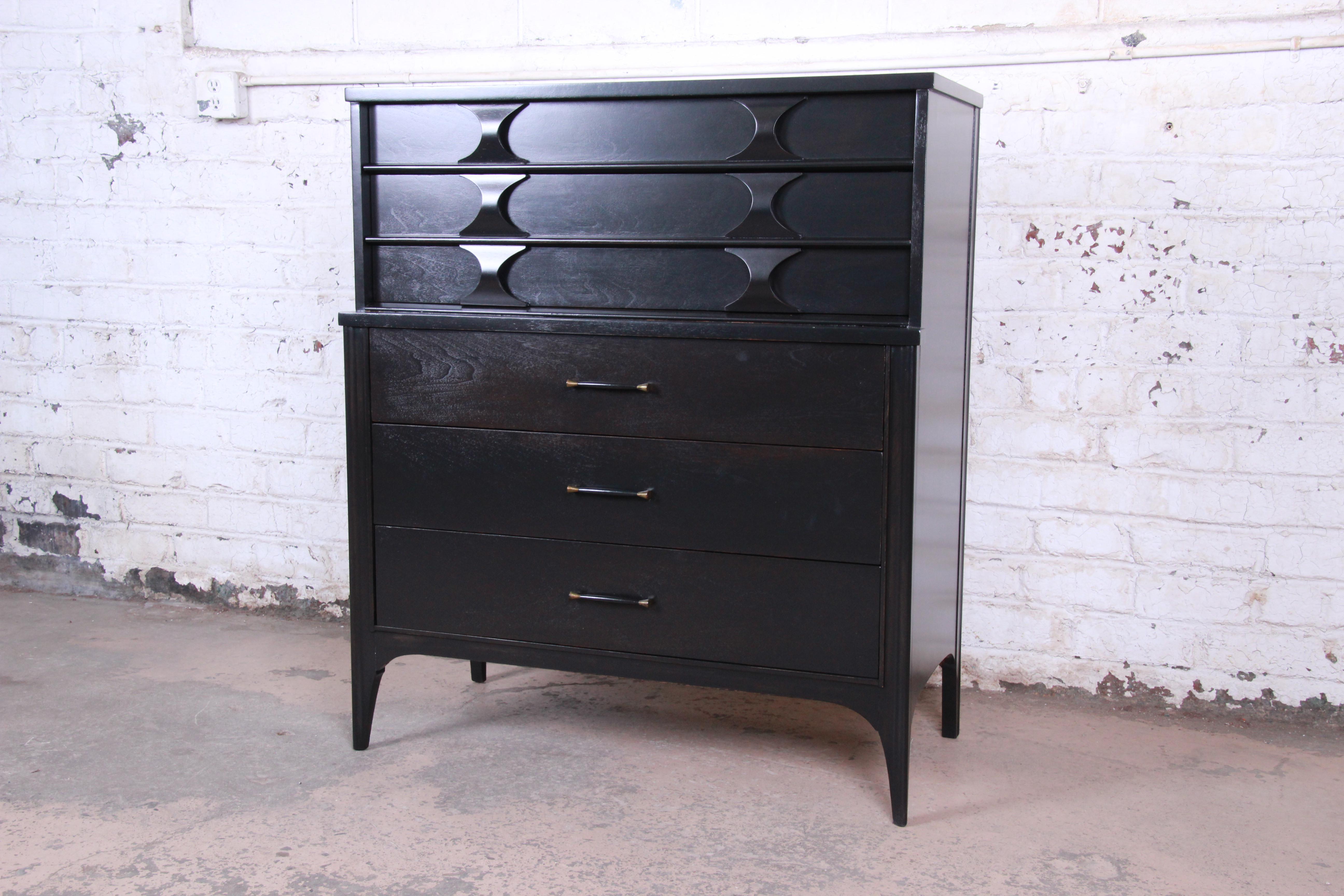 A gorgeous Mid-Century Modern sculpted walnut highboy dresser from the Perspecta line by Kent Coffey. The dresser features beautiful walnut wood grain with a newly ebonized finish. It offers great storage, with five deep dovetailed drawers. The