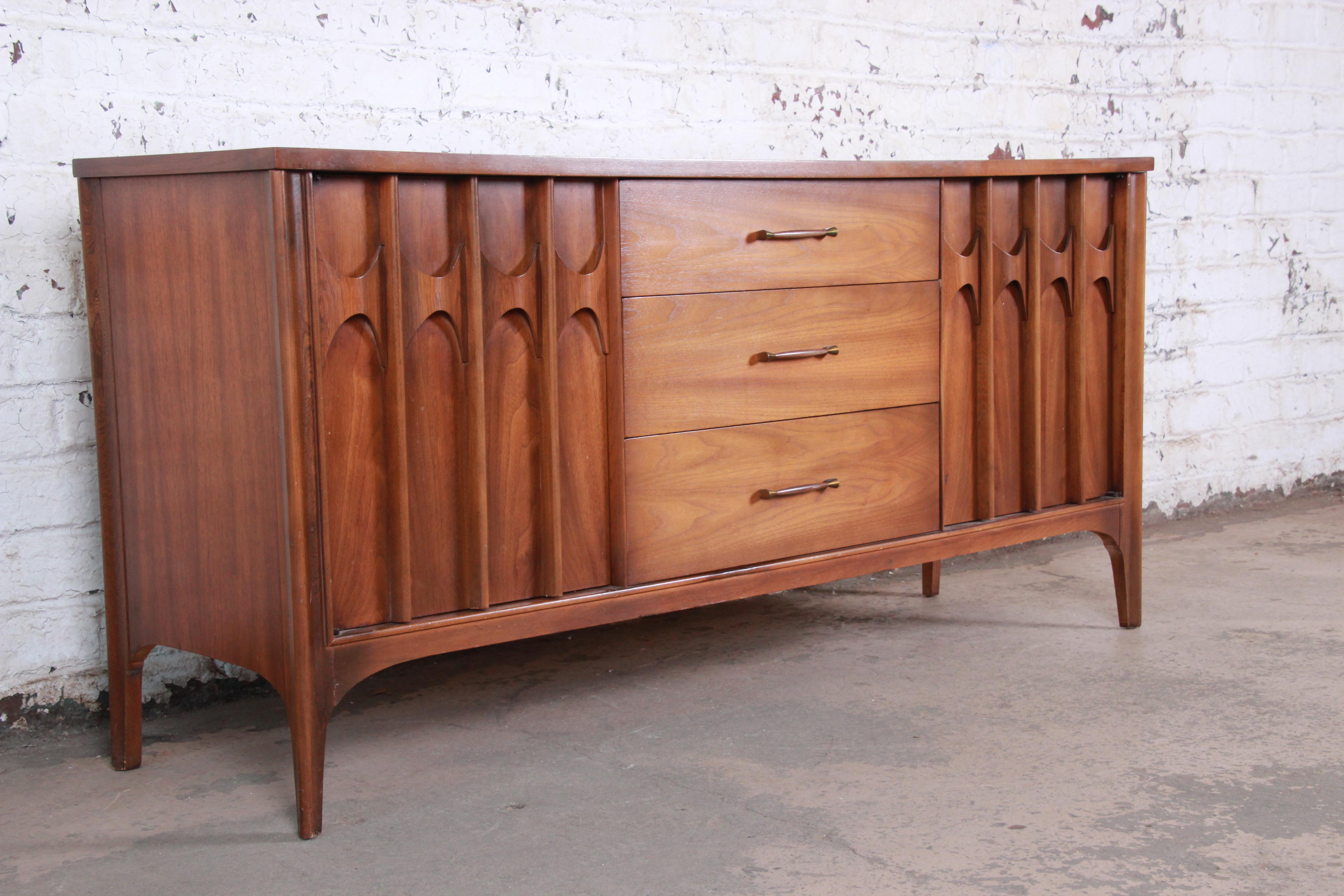 A gorgeous Mid-Century Modern credenza or sideboard from the Perspecta line by Kent Coffey. The credenza features stunning walnut wood grain with a sculpted arched rosewood design on the door fronts. It offers ample storage, with three dovetailed