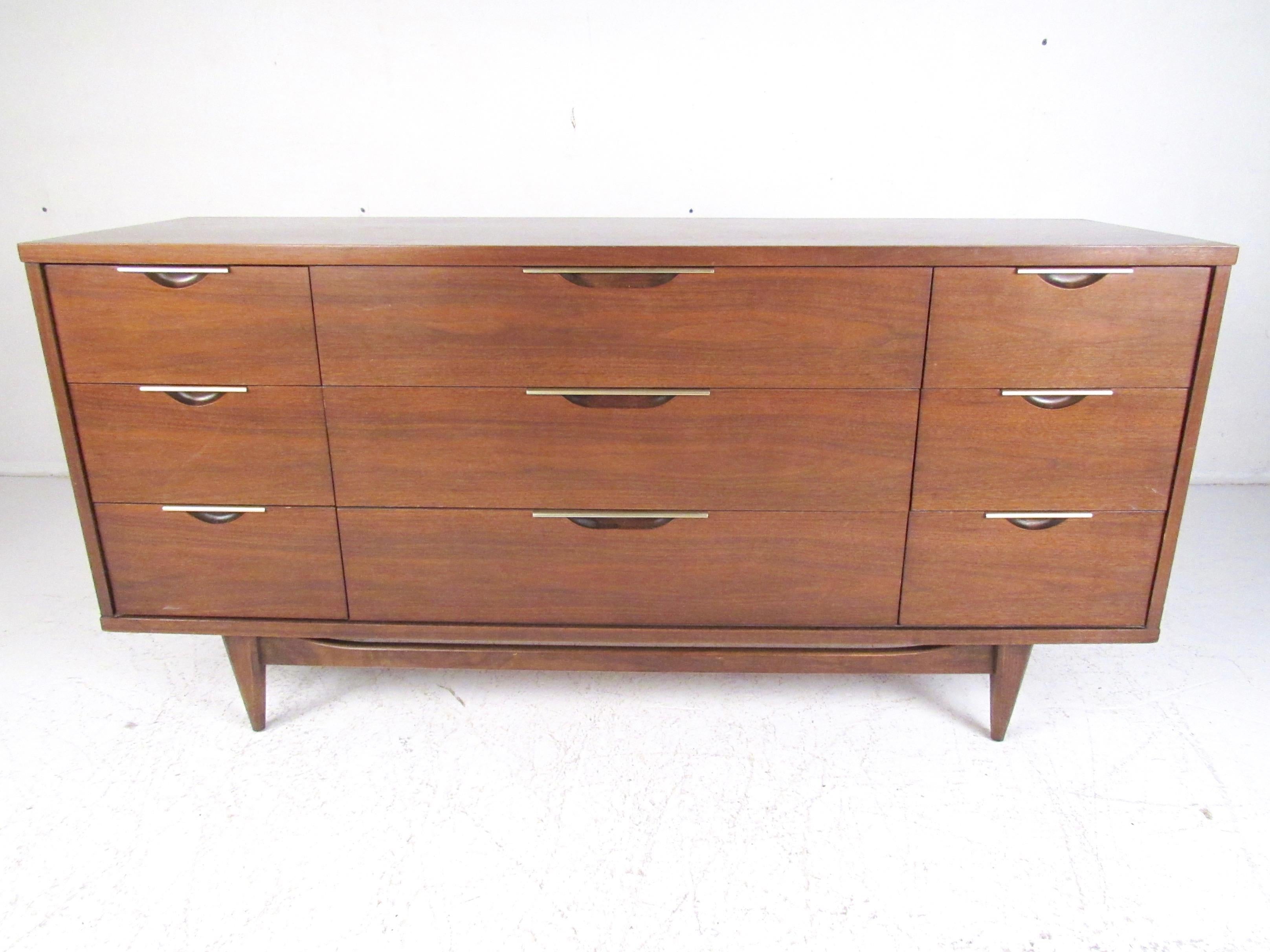 This nine-drawer bedroom dresser by Kent Coffey features walnut finish, metallic trim, and tapered midcentury style legs. Spacious dove-tailed drawers add plenty of storage to bedroom or otherwise, while the striking vintage modern design of this