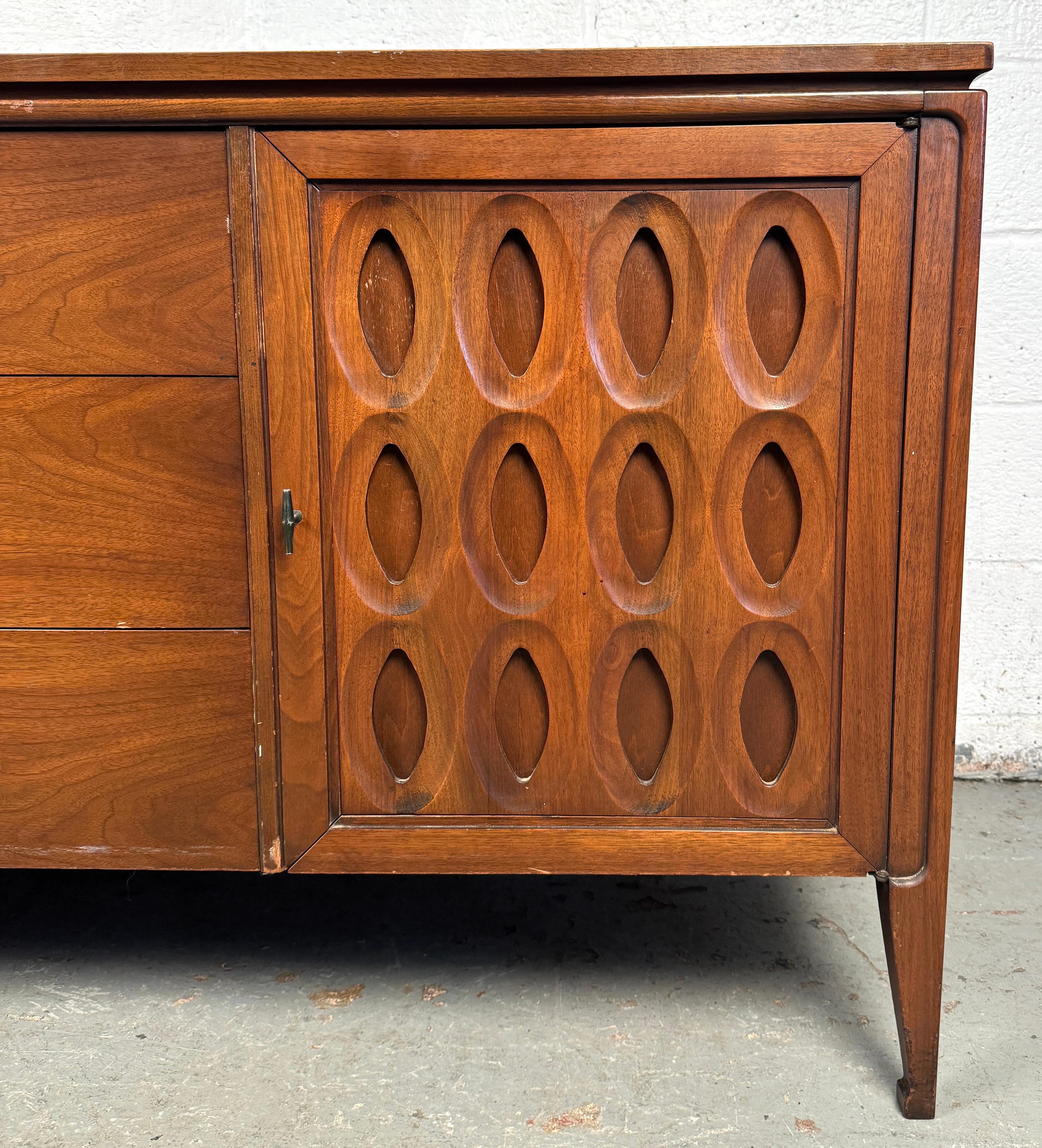 Comò in noce di Kent Coffey, dalle linee pulite di metà secolo, con cassetti scolpiti e venature calde del legno. Un'ampia capienza con un profilo raffinato e moderno: un pezzo iconico del design americano degli anni Sessanta. Conferma il luogo di