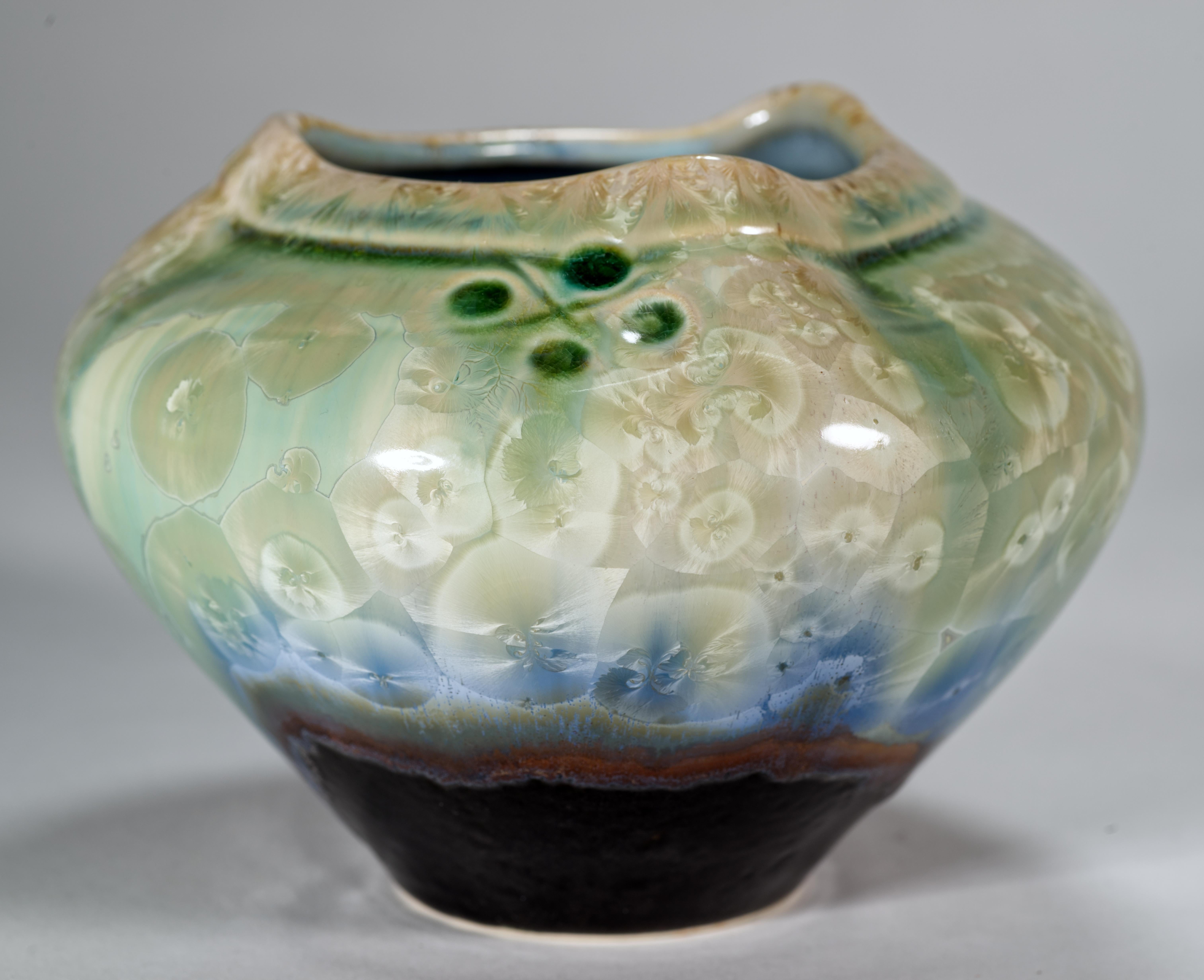  El llamativo jarrón de Studio Pottery presenta un esmalte cristalino en brillantes pero armoniosos tonos verde azulado, gris y beige en la parte superior del jarrón, y esmalte goteado naranja quemado y marrón espresso en la parte inferior. El