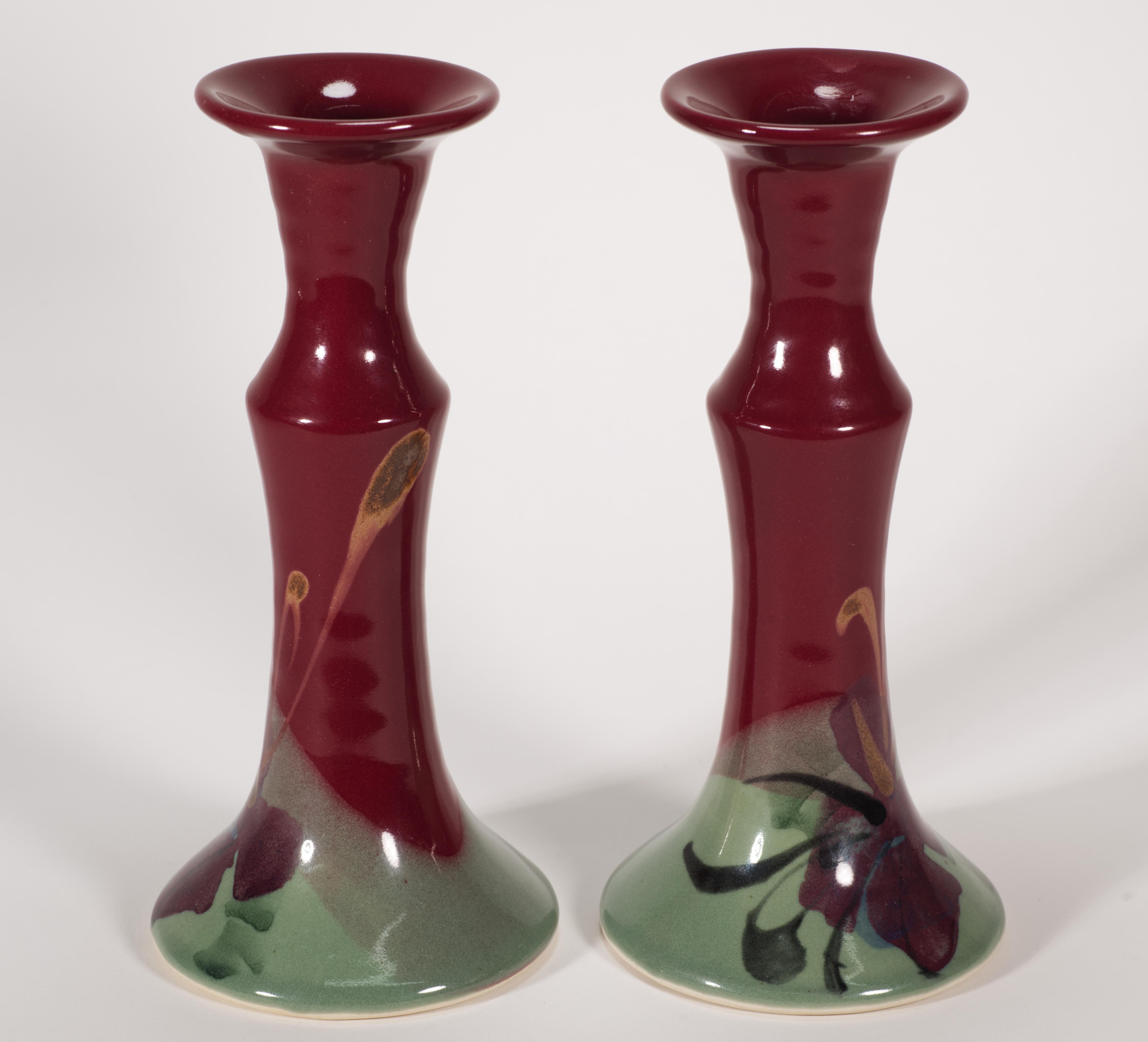  La coppia di candelieri in ceramica vintage è stata realizzata da Kent Follette di Follette Pottery in stile minimalista e organico. I pezzi sono decorati con disegni floreali astratti in varie tonalità di rosso scuro, nero e blu con accenti di