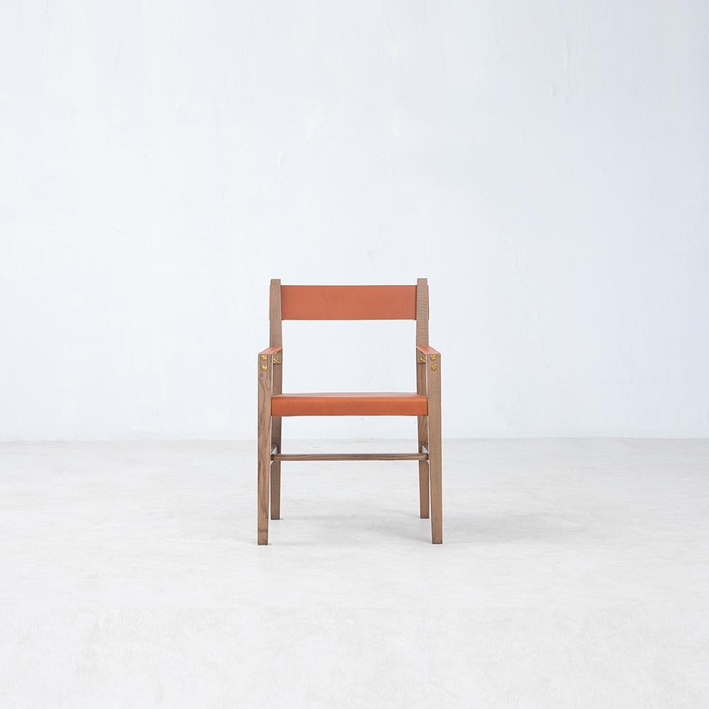 Un jeu de matériaux sans faille, le fauteuil Kent associe le frêne blanc certifié FSC® et le cuir épais de première qualité à une menuiserie élégante et à une quincaillerie en acier finement finie au laiton pour en faire une chaise de salle à manger