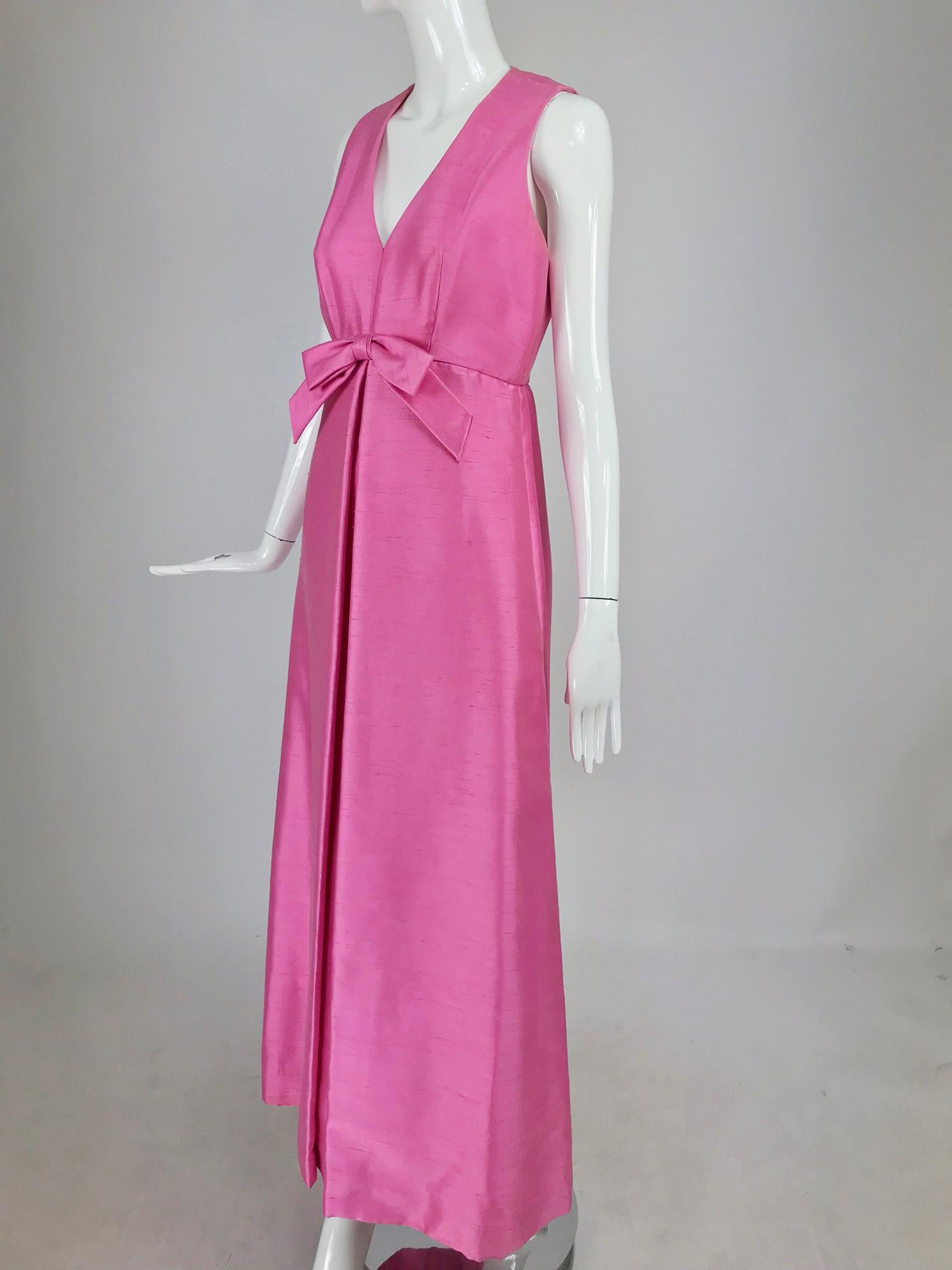 Kent Originals bubble gum pink slub silk bow front evening dress from the 1960s. This beautiful gown is a classic. Sleeveless gown with V neckline and darted bodice. The seamed waist has a self bow at the center, the long A line skirt has an