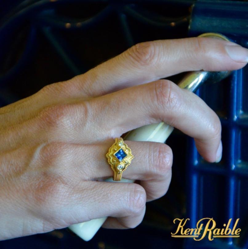 With a Princess Cut Sapphire at it's apex, this three stone ring tells the story of Kent's unique style. You can see here that we have first a band of gold, with detail set around yet another band of gold. Atop that, another layer of fine