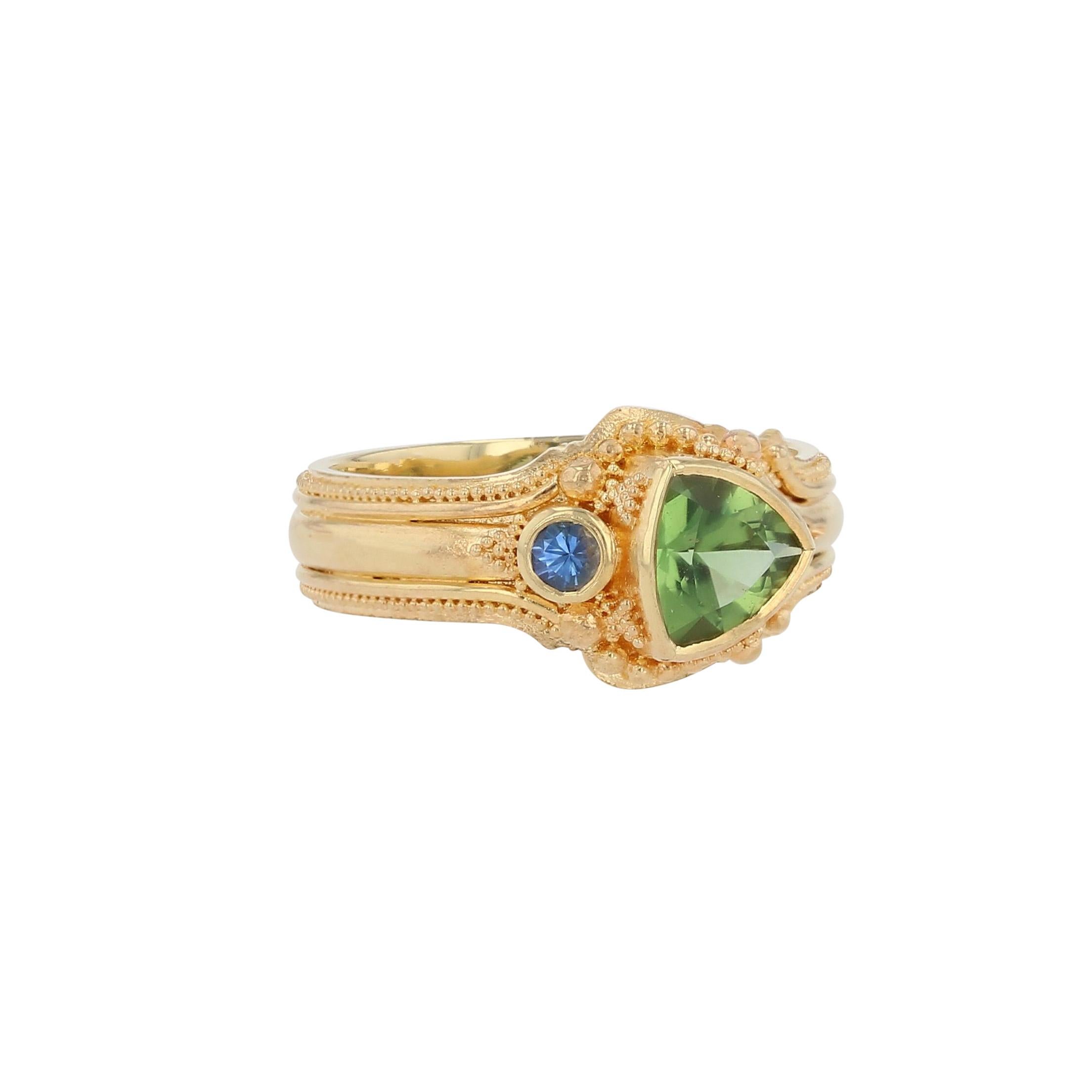 La bague asymétrique de Kent Raible est un trésor de détails complexes, d'intérêt et de couleurs. Serti dans de l'or 18 carats, le bleu doux et plein du petit saphir s'accorde parfaitement avec la couleur luxuriante de la tourmaline Seafoam taillée