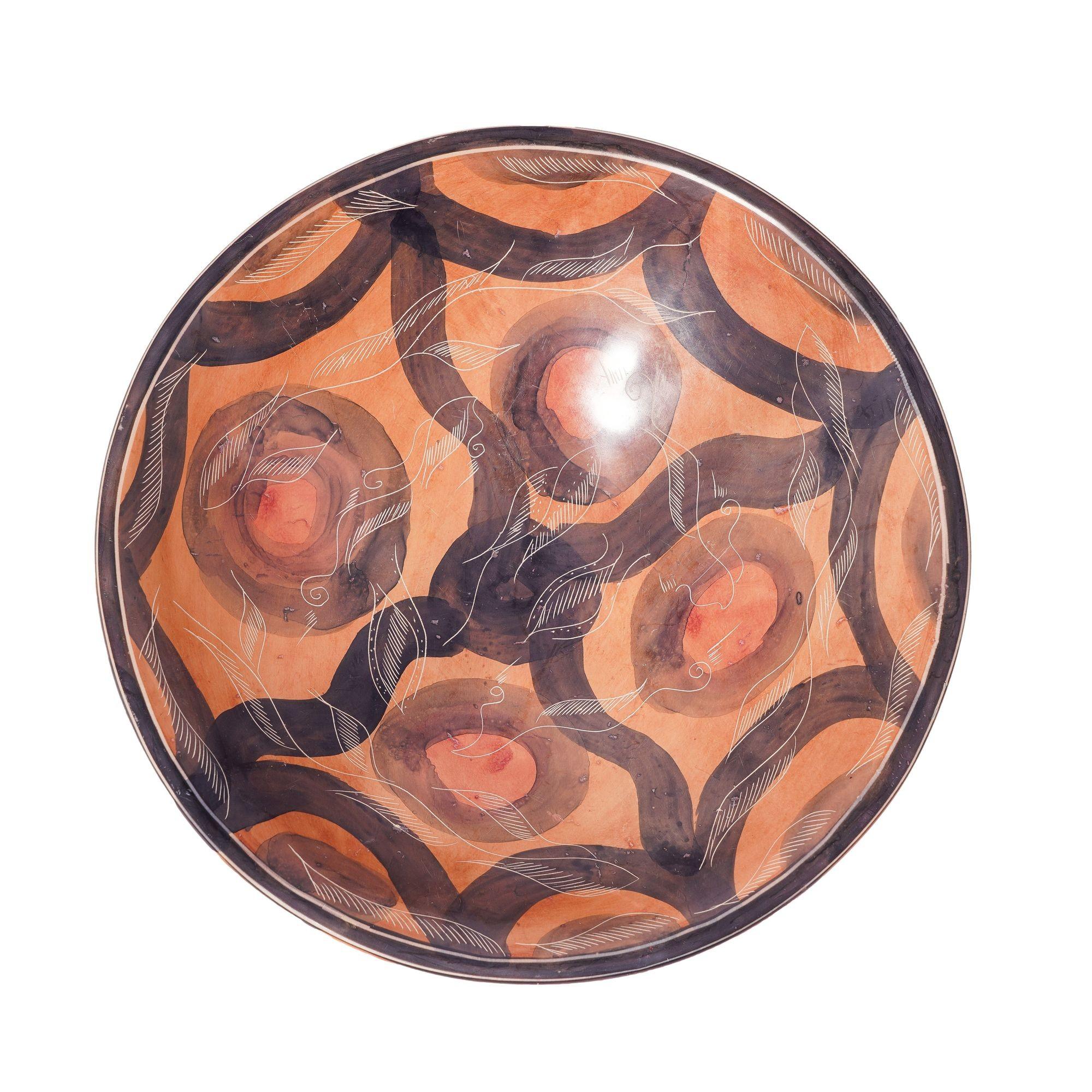 Sgraffito carved & painted circular soapstone shallow footed bowl. The interior of the bowl is decorated in a red ochre ground with faded purple circles centered with a red dot. A dark purple scolloped border is joined by four fluid dark purple