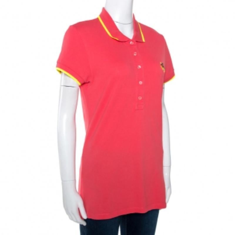 This lovely polo t-shirt comes from the house of Kenzo.  It is crafted from 100% cotton and flaunts a lovely shade of coral pink. It is styled with a simple collar, short sleeves, button closure and an embroidered tiger motif ont the front. It is