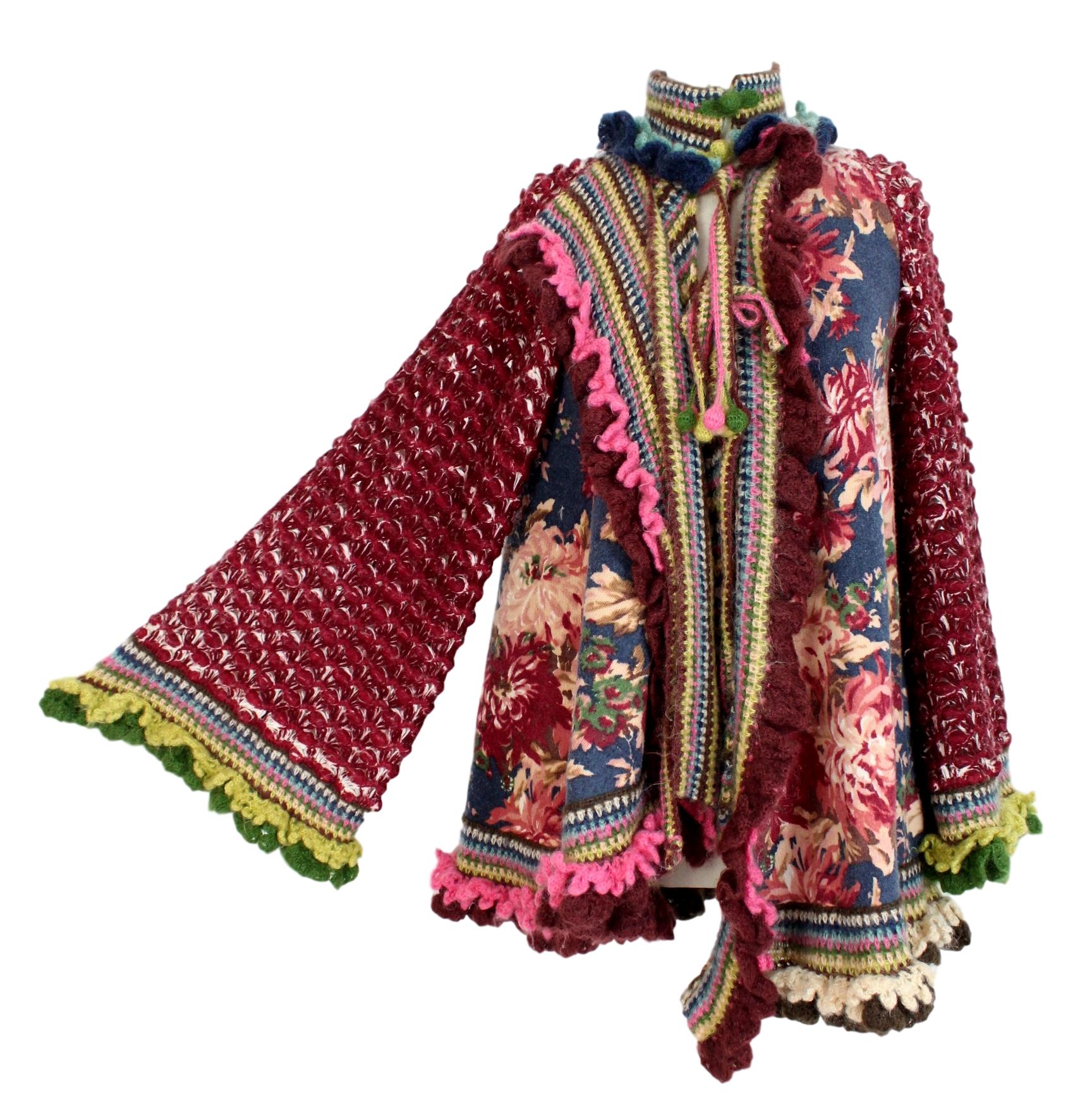 Kenzo Defile vintage 90s women's poncho. Multicolored wool jacket, blue and burgundy floral designs. Wide batwing sleeves, perforated, closure with laces and pom poms. High collar, asymmetrical in the front length. Made in Italy. Very good vintage