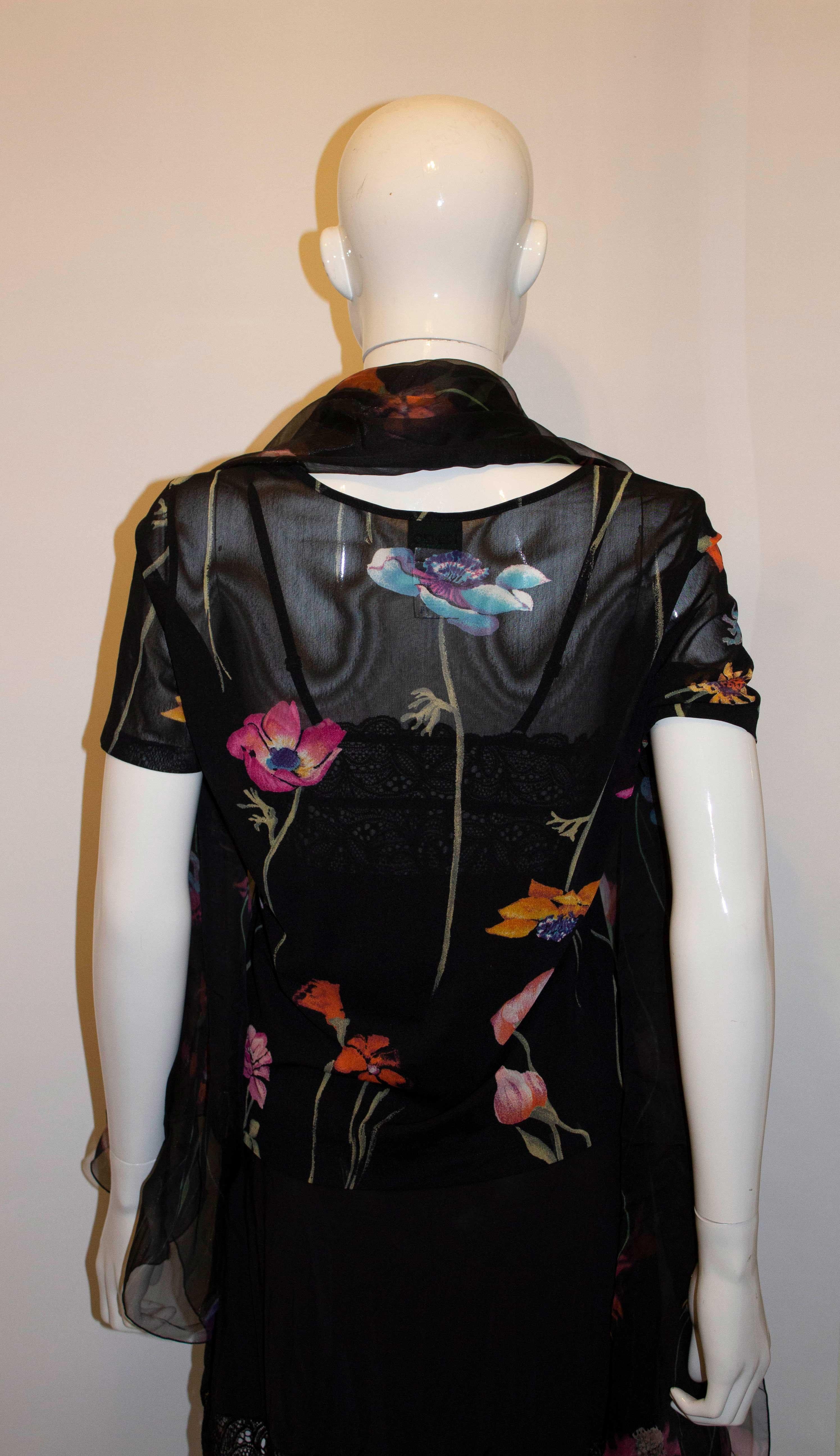 A pretty and easy to wear top by Kenzo with matching scarf. The top has a black background with floral print, and has a round neckline. Measurements: Bust 39'', length 42''. It has a matching scarf measuring 26'' x 69''