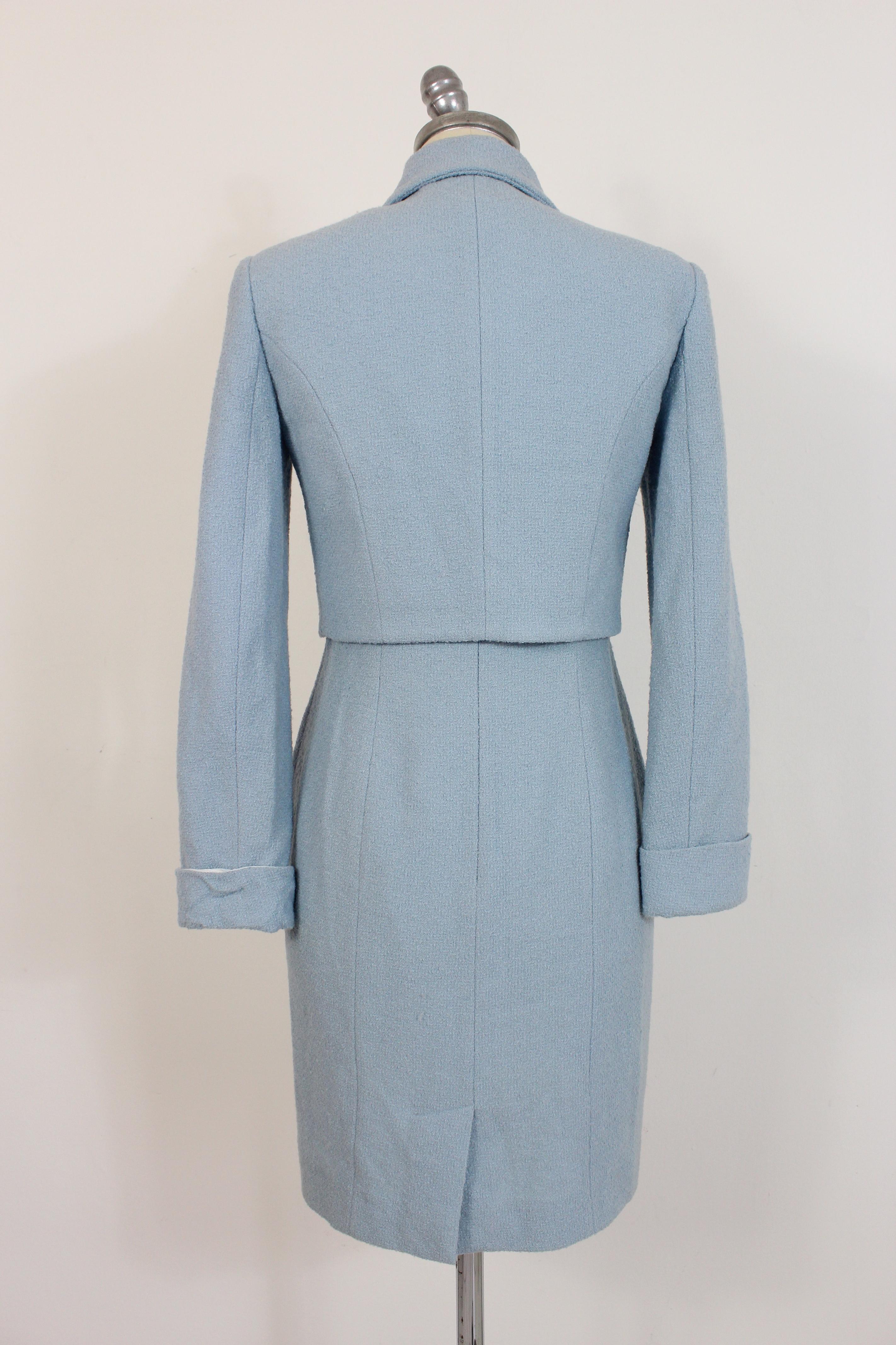 Robe de tailleur pour femme vintage des années 90, Kenzo By. Veste à taille courte, robe fourreau avec nœud sur la poitrine, fermeture à glissière sur l'épaule. Couleur bleu clair, tissu 96% laine 4% polyamide. Fabriqué en France. La taille de la